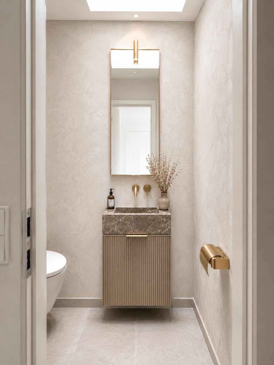 Modernes Badezimmer mit Waschbecken, Spiegel, WC und goldfarbenem Toilettenpapierhalter.