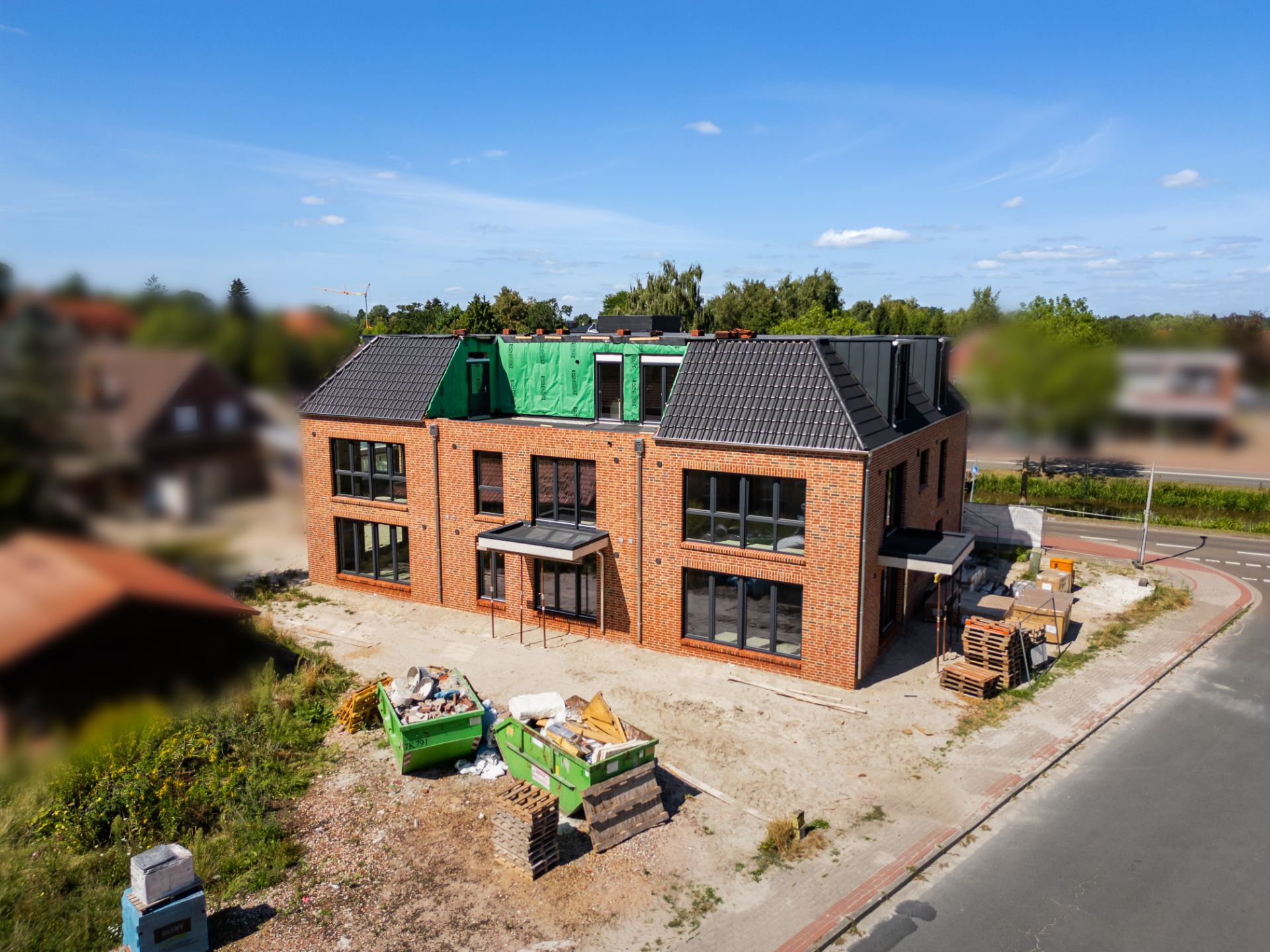 Neues zweistöckiges Backsteinhaus im Bau, umgeben von Baustellenmaterialien.