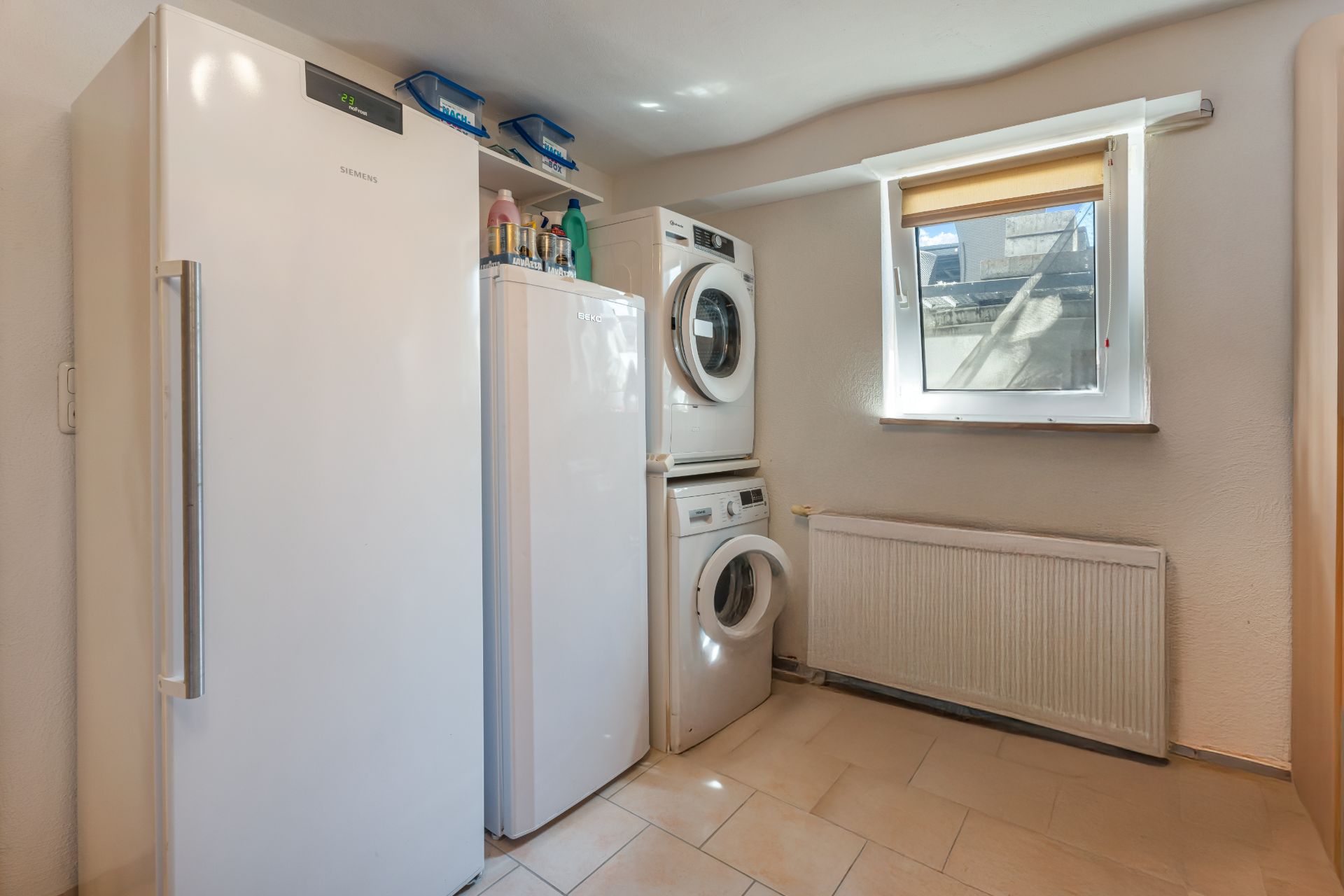 Hauswirtschaftsraum mit Gefrierschrank, Waschmaschine und Trockner sowie einem Fenster.