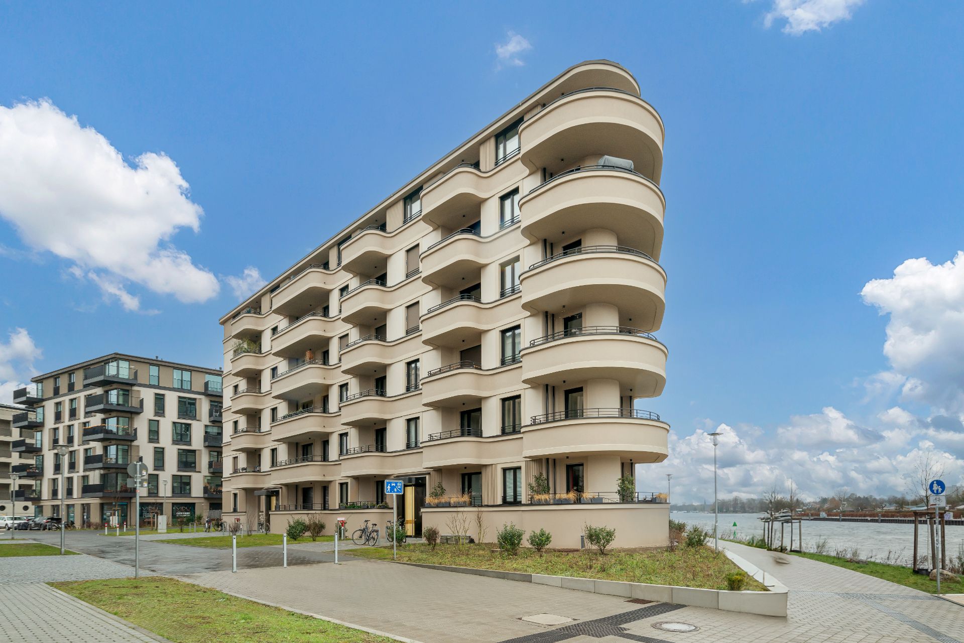 Mehrstöckiges Wohnhaus mit geschwungenen Balkonen und angrenzendem Gehweg.