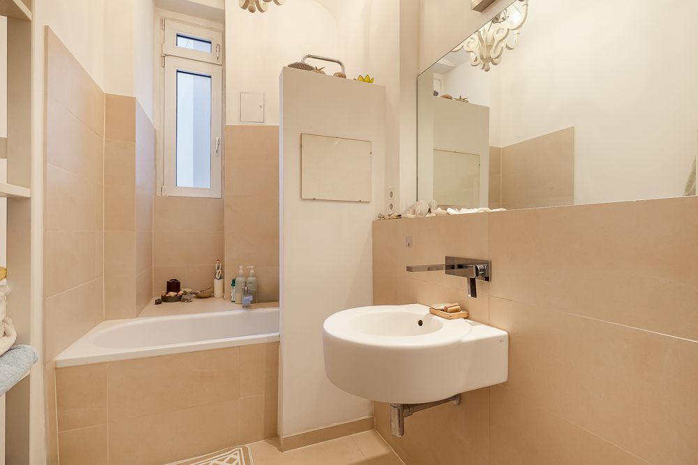Modernes Badezimmer mit Badewanne, Waschbecken und großem Spiegel.