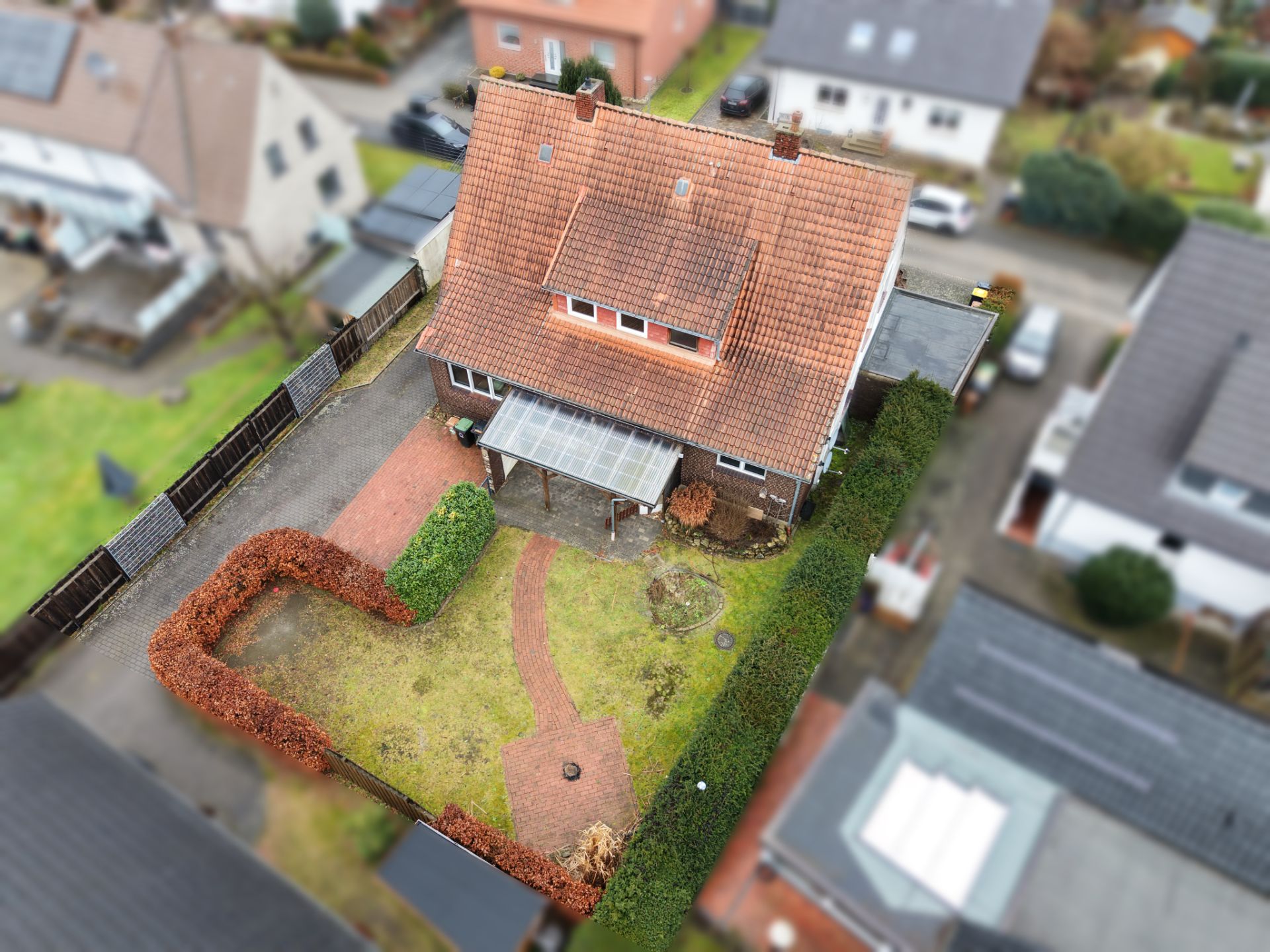Luftaufnahme eines Einfamilienhauses mit Garten, Gehweg und überdachter Terrasse.