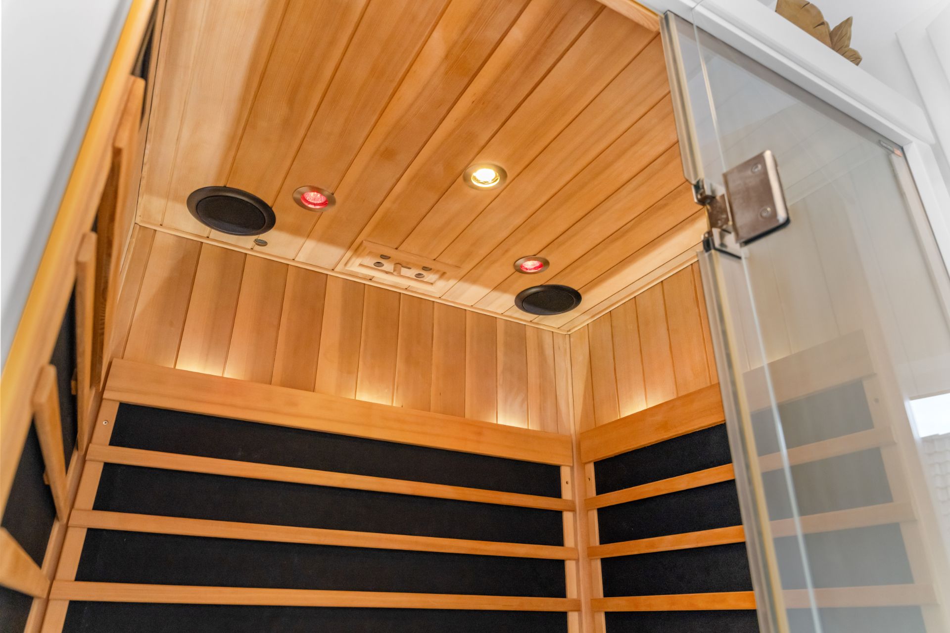 Holzsauna mit Glastür und eingebauten Deckenlampen in einem Wohnhaus.