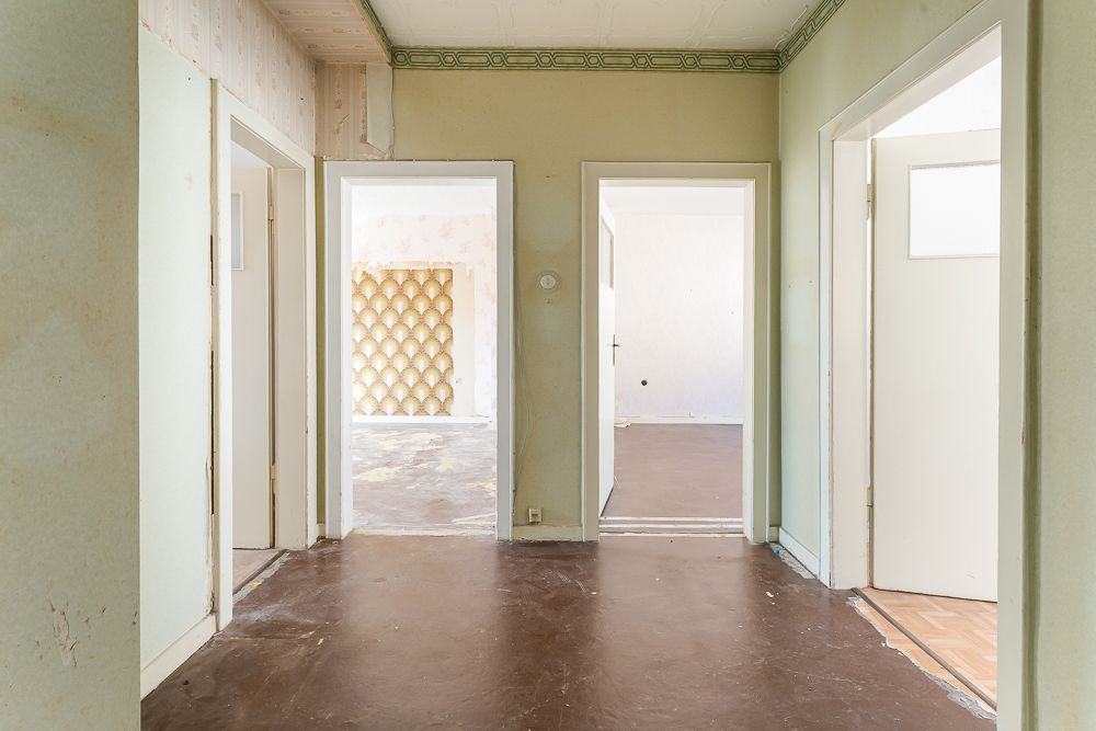 Blick in einen leeren Flur mit mehreren offenen Türen zu angrenzenden Zimmern.