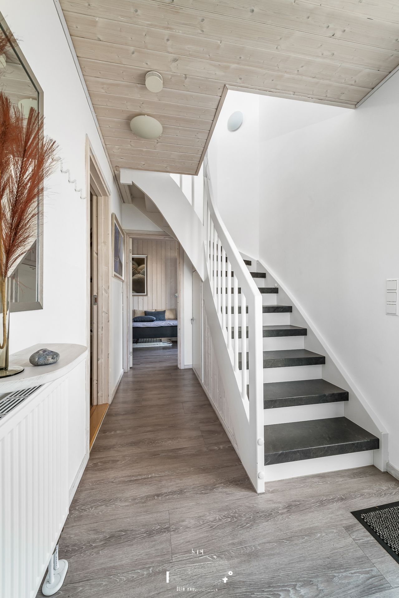 Heller Flur mit Holzdecke, Treppe und Blick in ein Wohnzimmer.