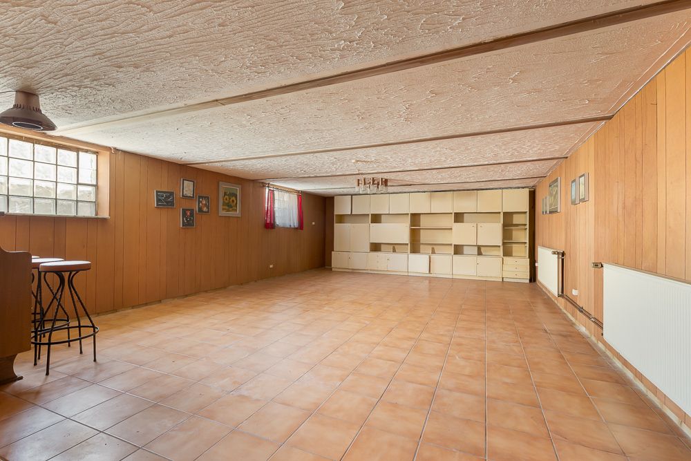 Geräumiger Kellerraum mit Fliesenboden, Holzvertäfelung und Einbauschränken an der Rückwand.
