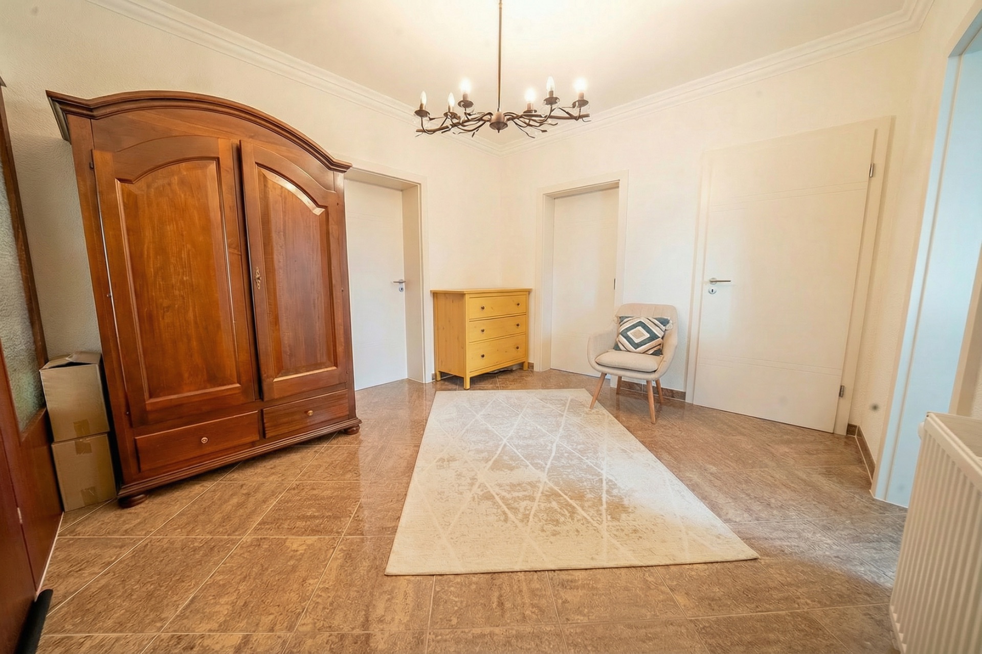 Heller Flur mit Holzschrank, gelber Kommode, Sessel und Teppich auf braunem Boden.