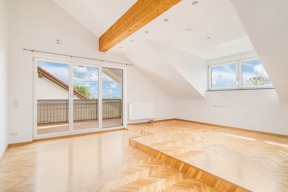 Helles Zimmer mit Stufe, Parkettboden, großen Fenstern und Zugang zu einem Balkon.