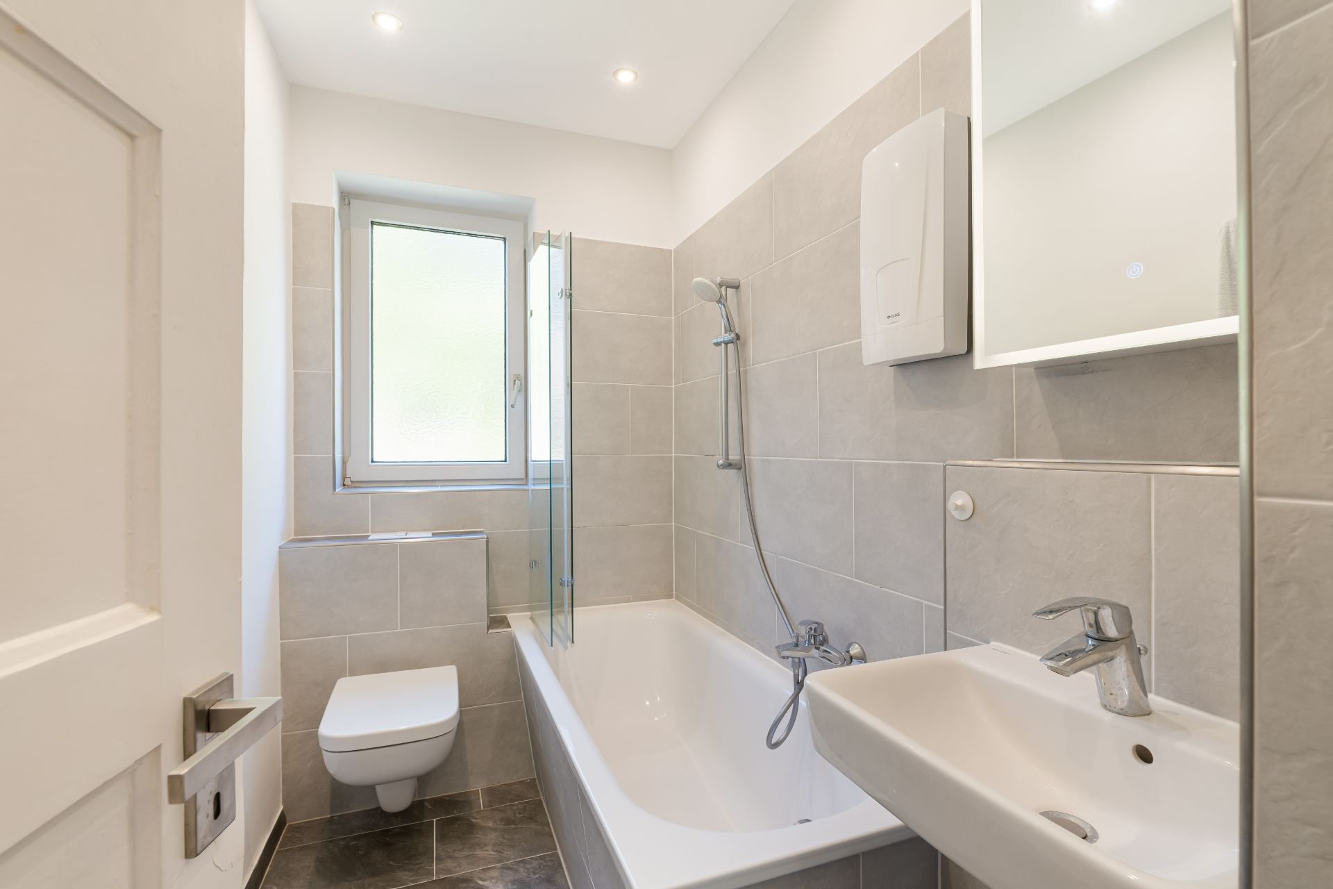 Modernes Badezimmer mit Badewanne, Toilette, Waschbecken und Fenster.