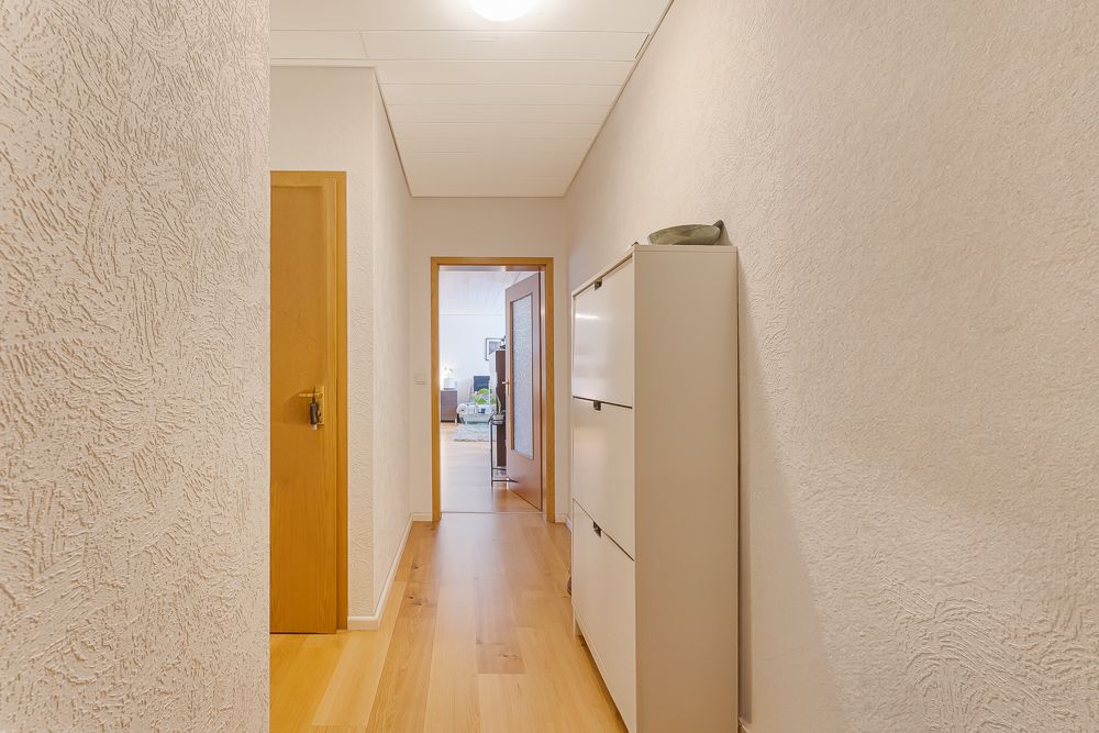 Heller Flur mit Holzfußboden, Tür links und Schrank rechts.