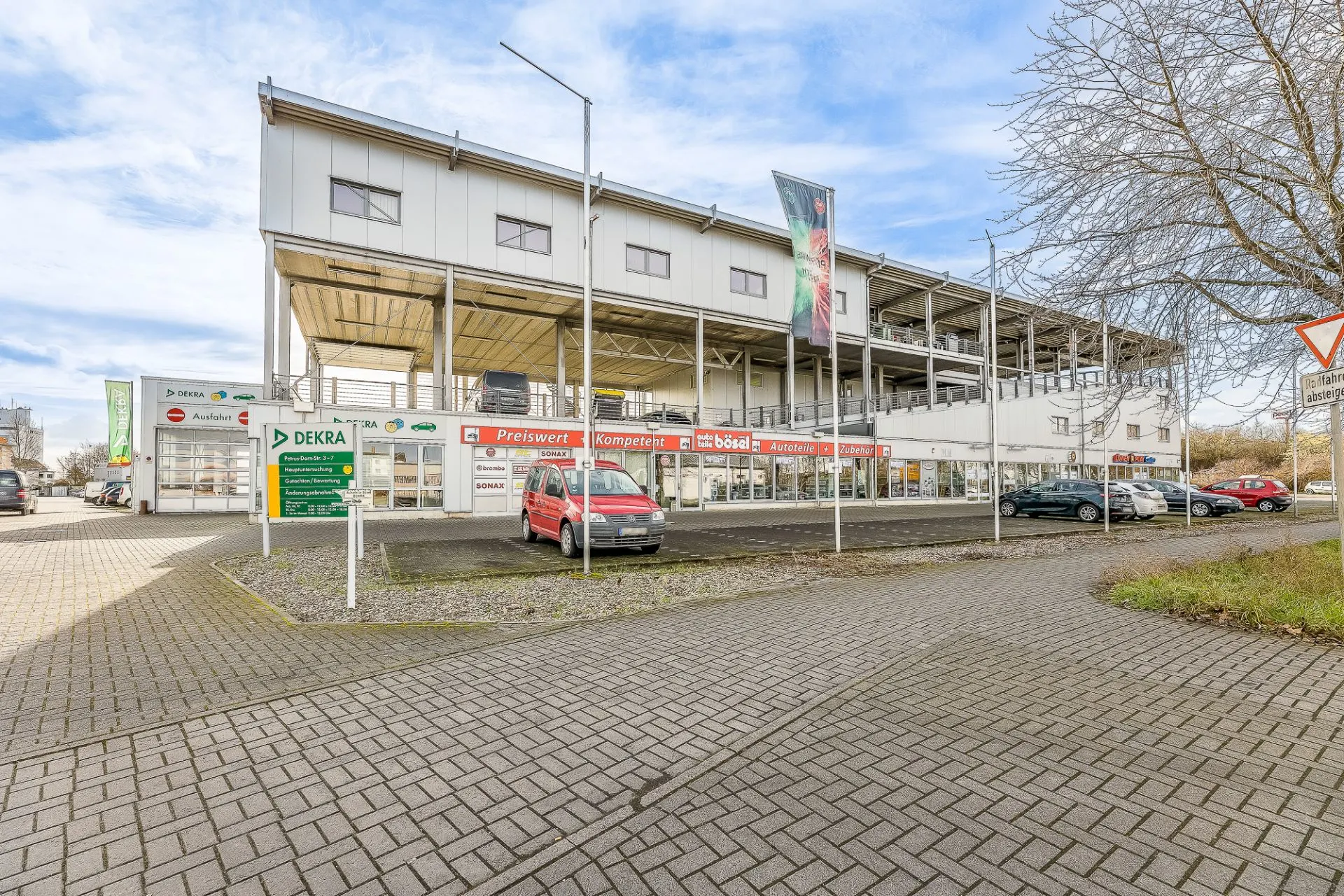 Großes zweistöckiges Geschäftsgebäude mit mehreren geparkten Autos davor.