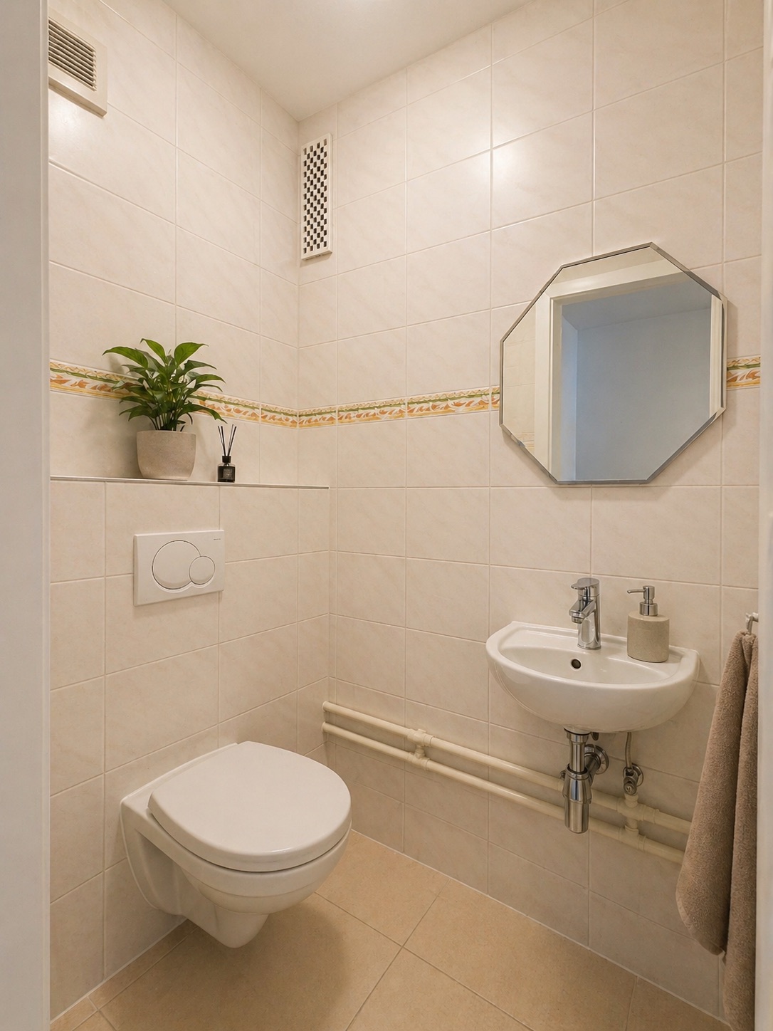 Kleines Badezimmer mit wandhängender Toilette, kleinem Waschbecken, Spiegel und Pflanze.