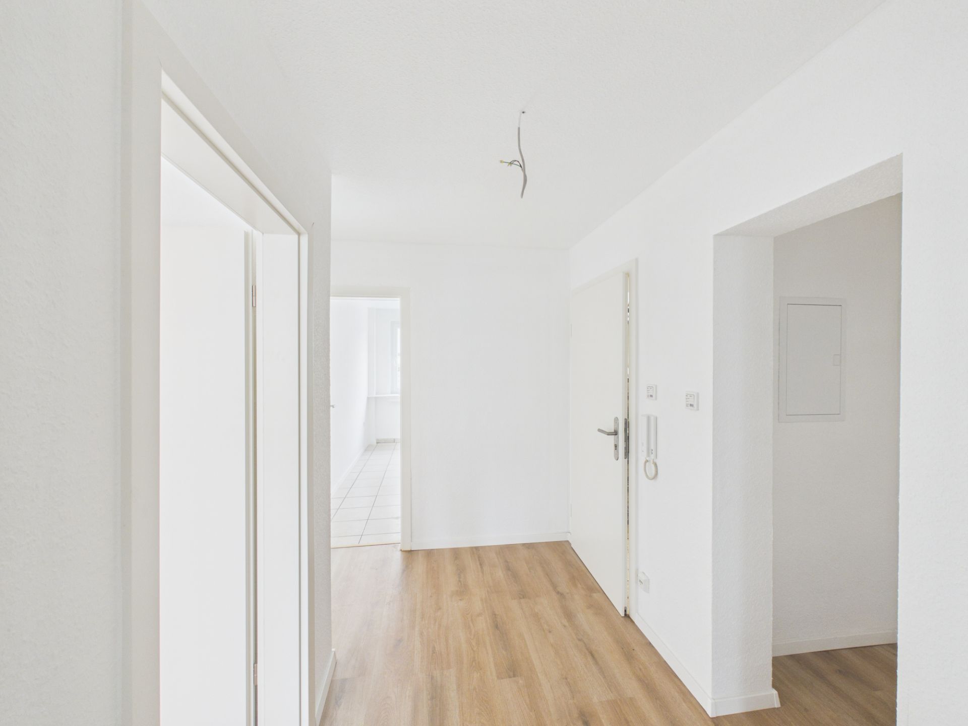 Heller Flur mit weiß gestrichenen Wänden und Parkettboden in einer Wohnung.