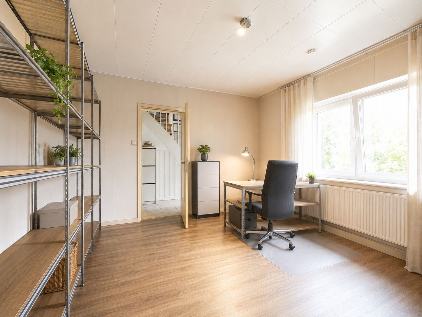 Helles Arbeitszimmer mit Schreibtisch, Regalen und großem Fenster.