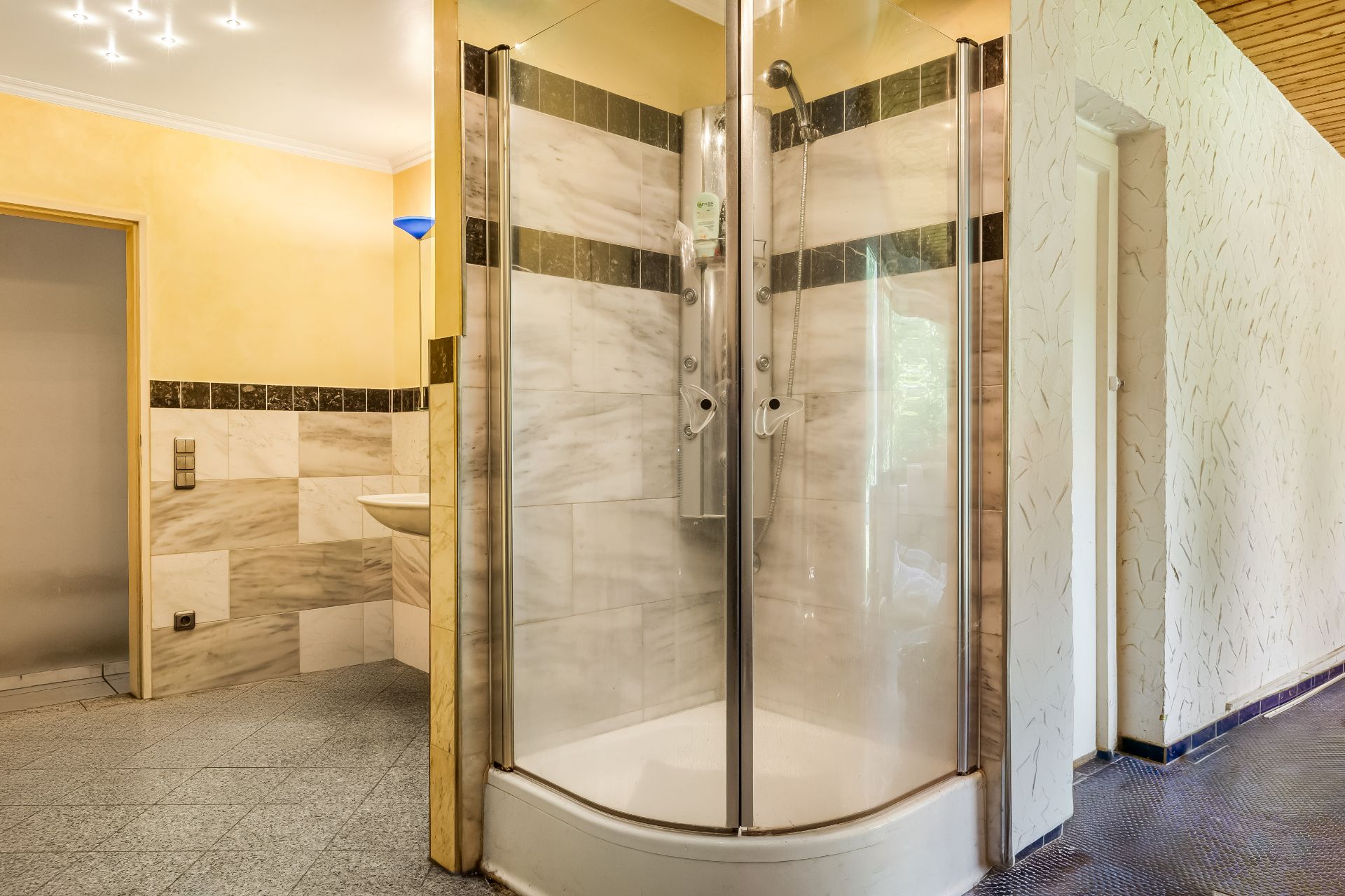 Moderne Dusche mit Glastüren in einem Badezimmer mit Fliesen und gelben Wänden.