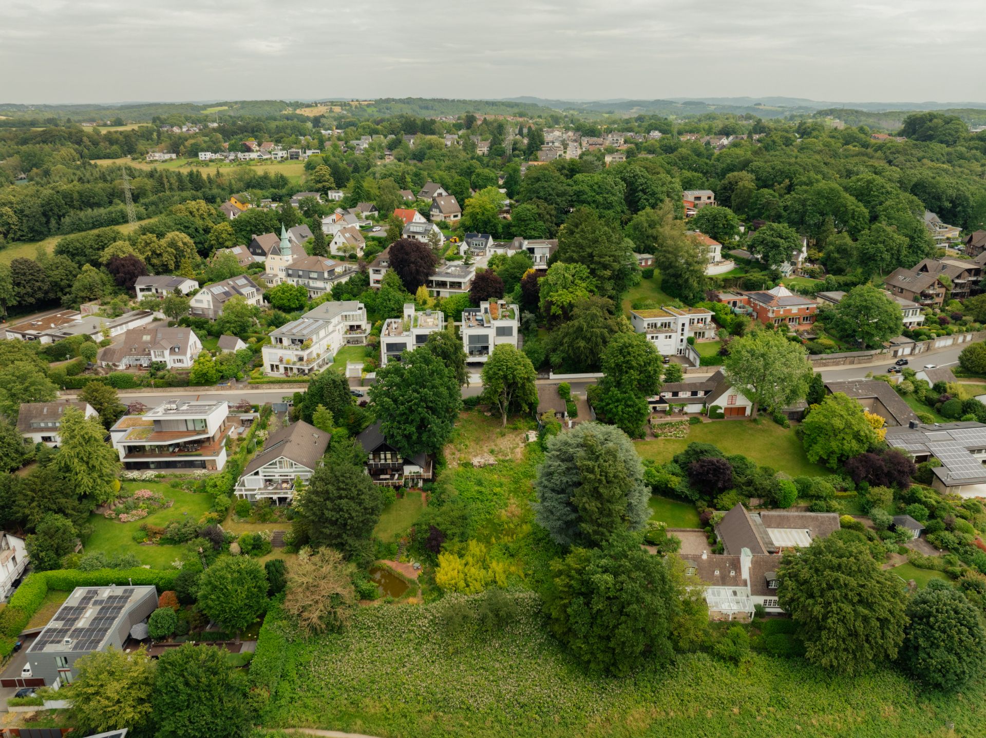 Luftaufnahme eines Wohnviertels mit vielen Häusern und viel grüner Vegetation.