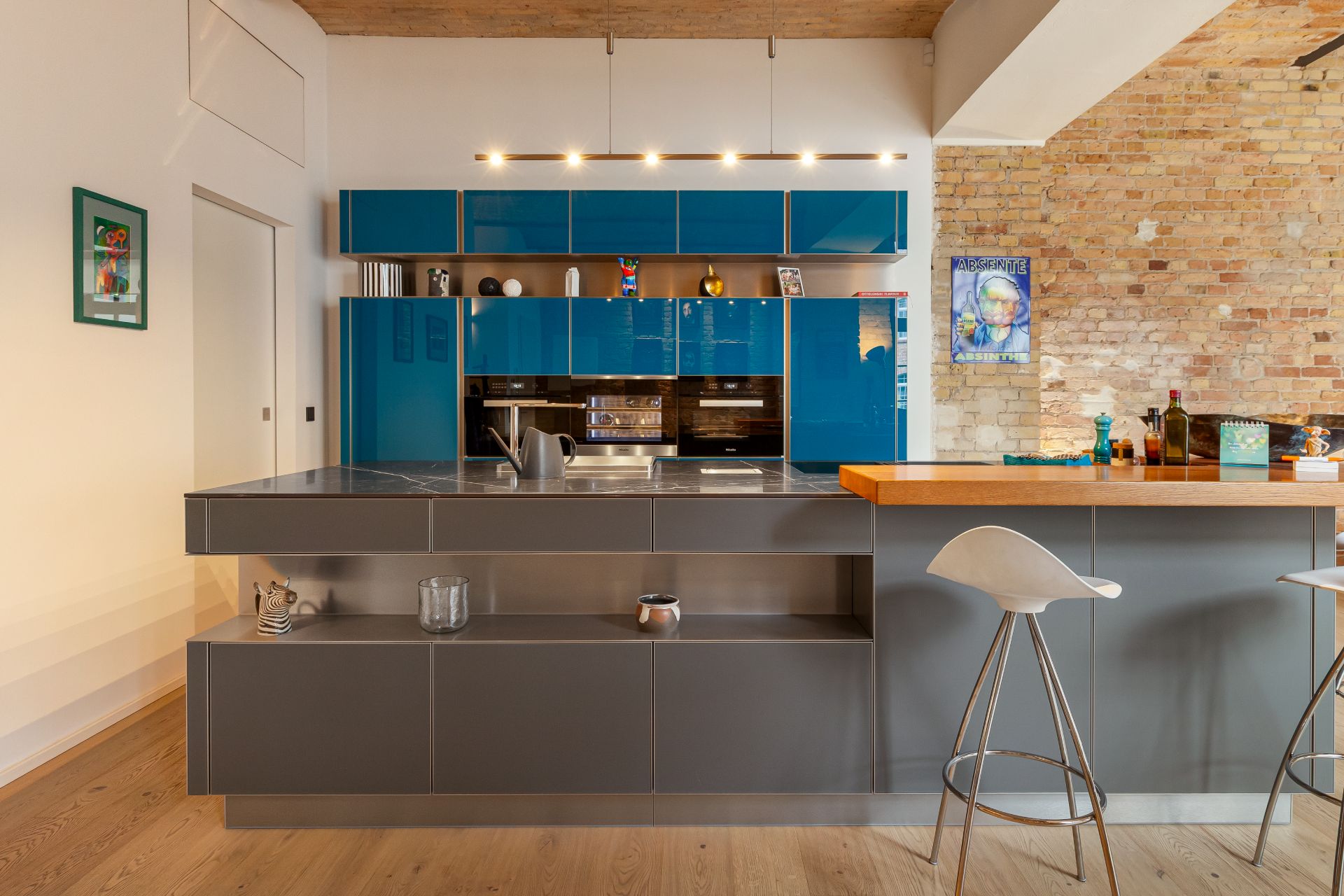 Moderne Küche mit blauen Schränken, grauer Theke und zwei weißen Barhockern.