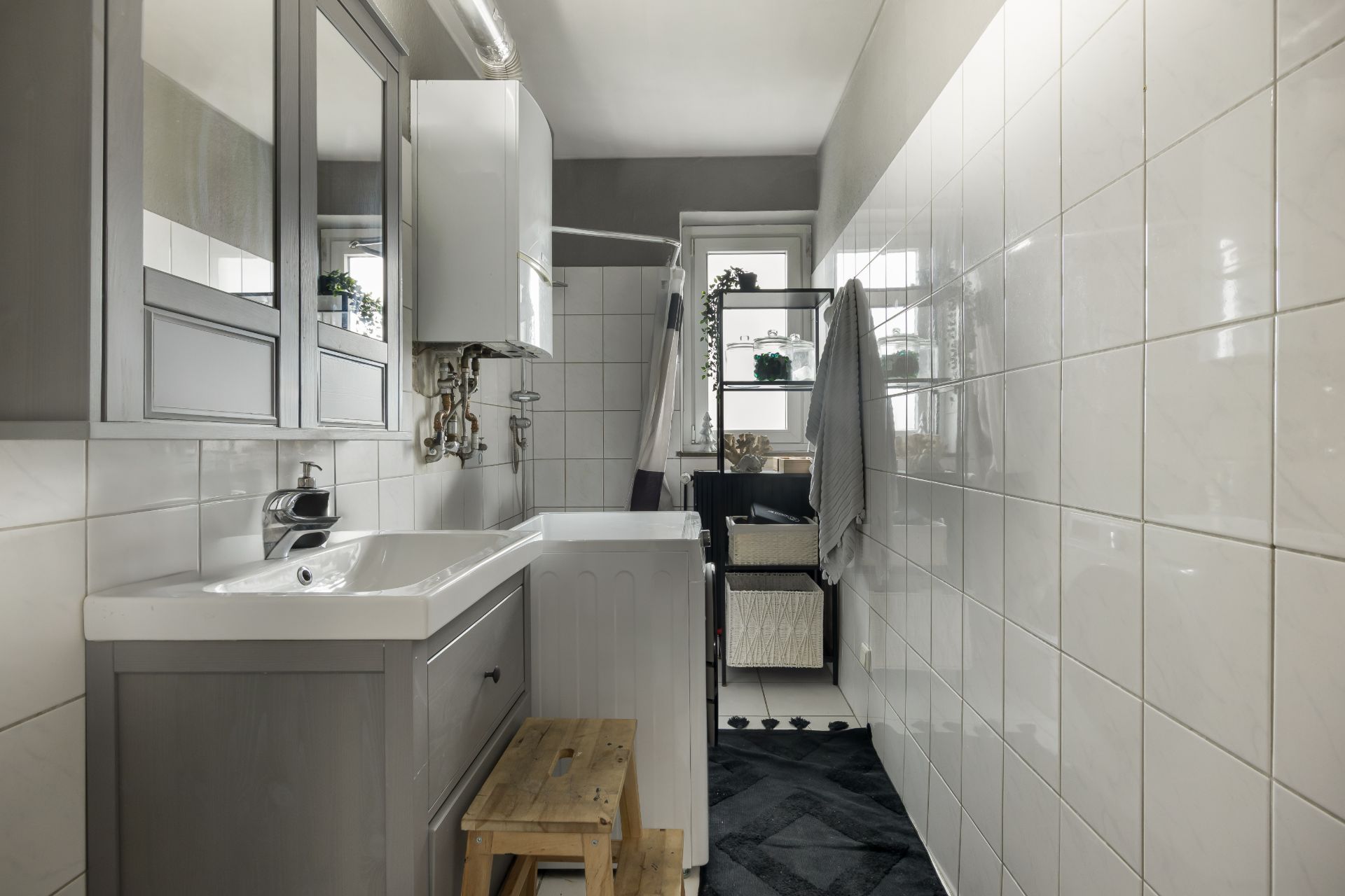 Modernes Badezimmer mit Waschbecken, Spiegel, Duschkabine und Fenster im Hintergrund.