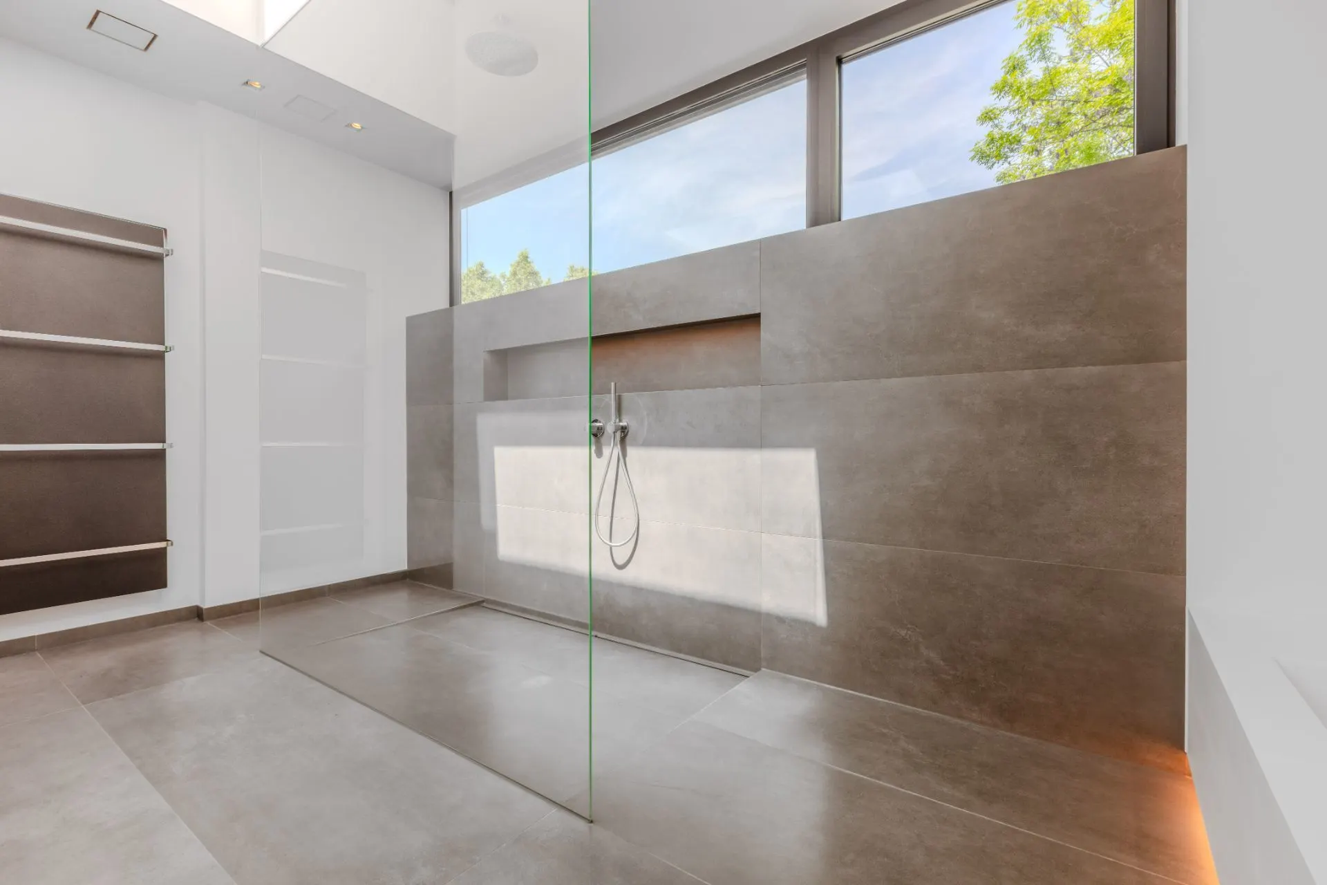 Modernes, helles Badezimmer mit großer bodenebener Dusche und großen Fenstern.