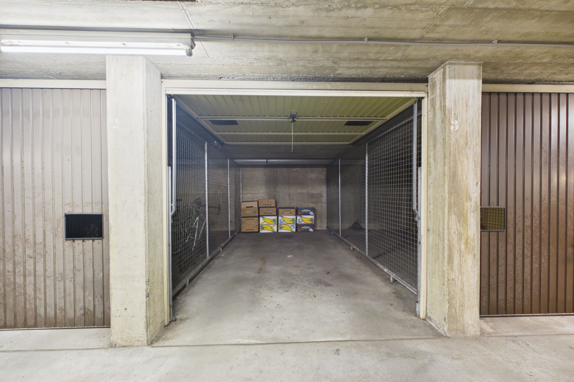 Geöffnete Garage mit einigen Kartons und Kisten im hinteren Bereich.