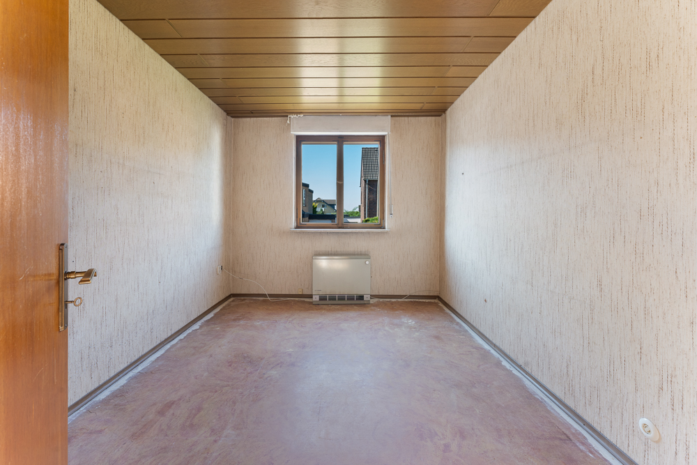 Leerer Raum mit offenem Holztür, Fenster und Heizkörper unter dem Fenster.