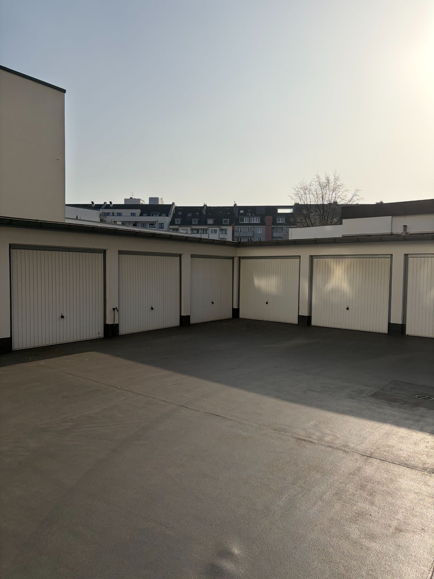 Mehrere geschlossene Garagentore in einem Innenhof bei Tageslicht.