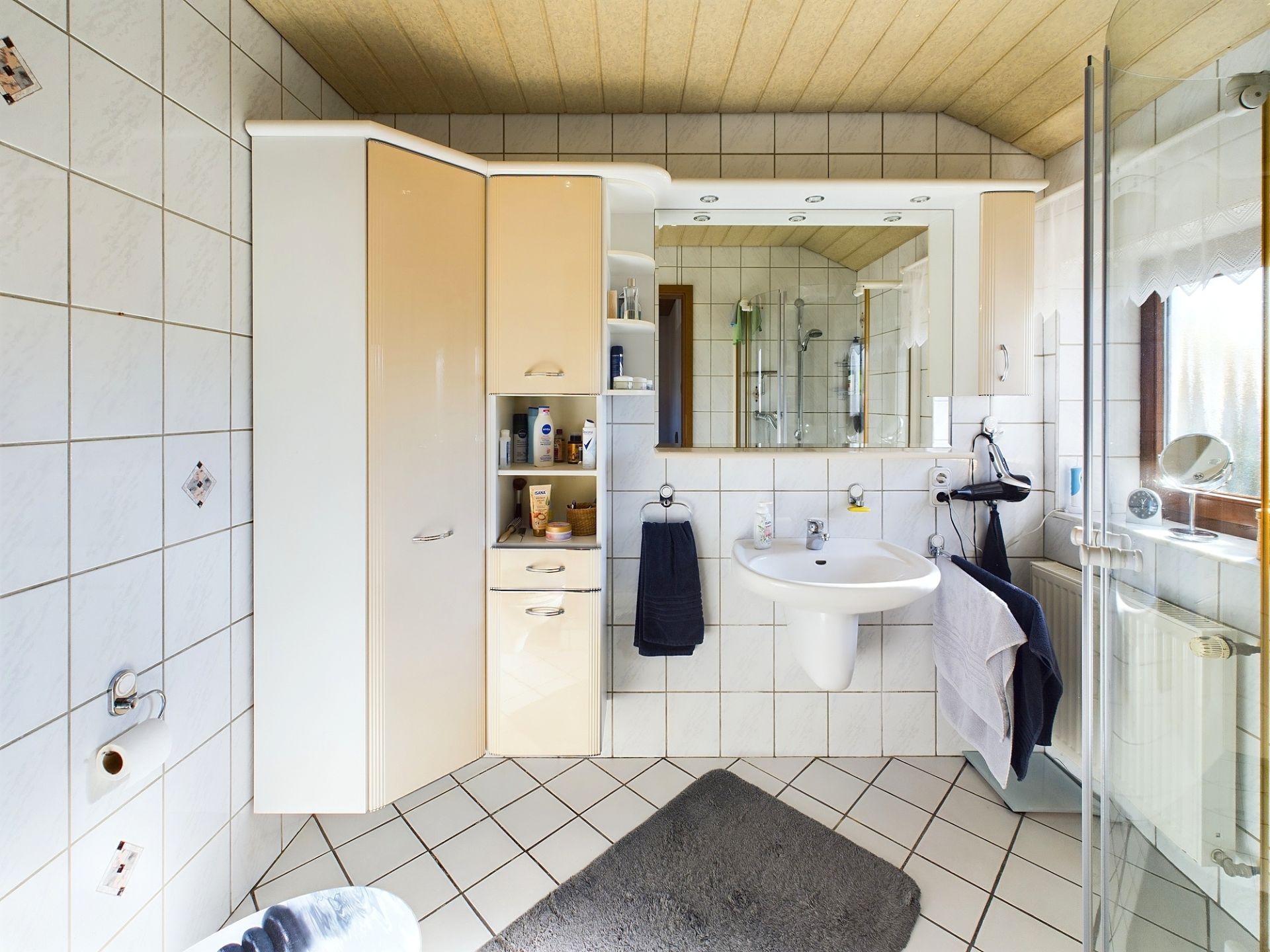 Modernes Badezimmer mit Spiegelschrank, Waschbecken, Dusche und großen Fenstern.