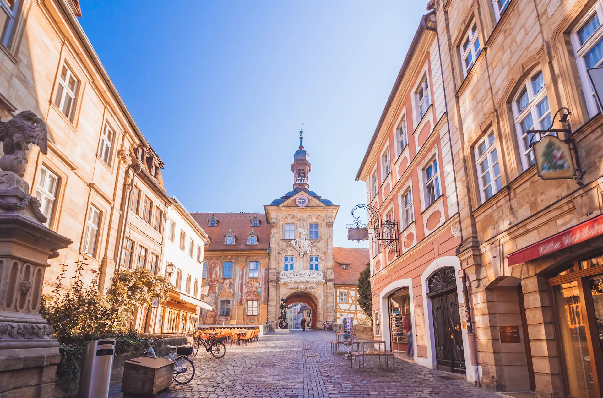 Historisches Gebäude mit bemalter Fassade und Turm, umgeben von alten Häusern und Kopfsteinpflaster.