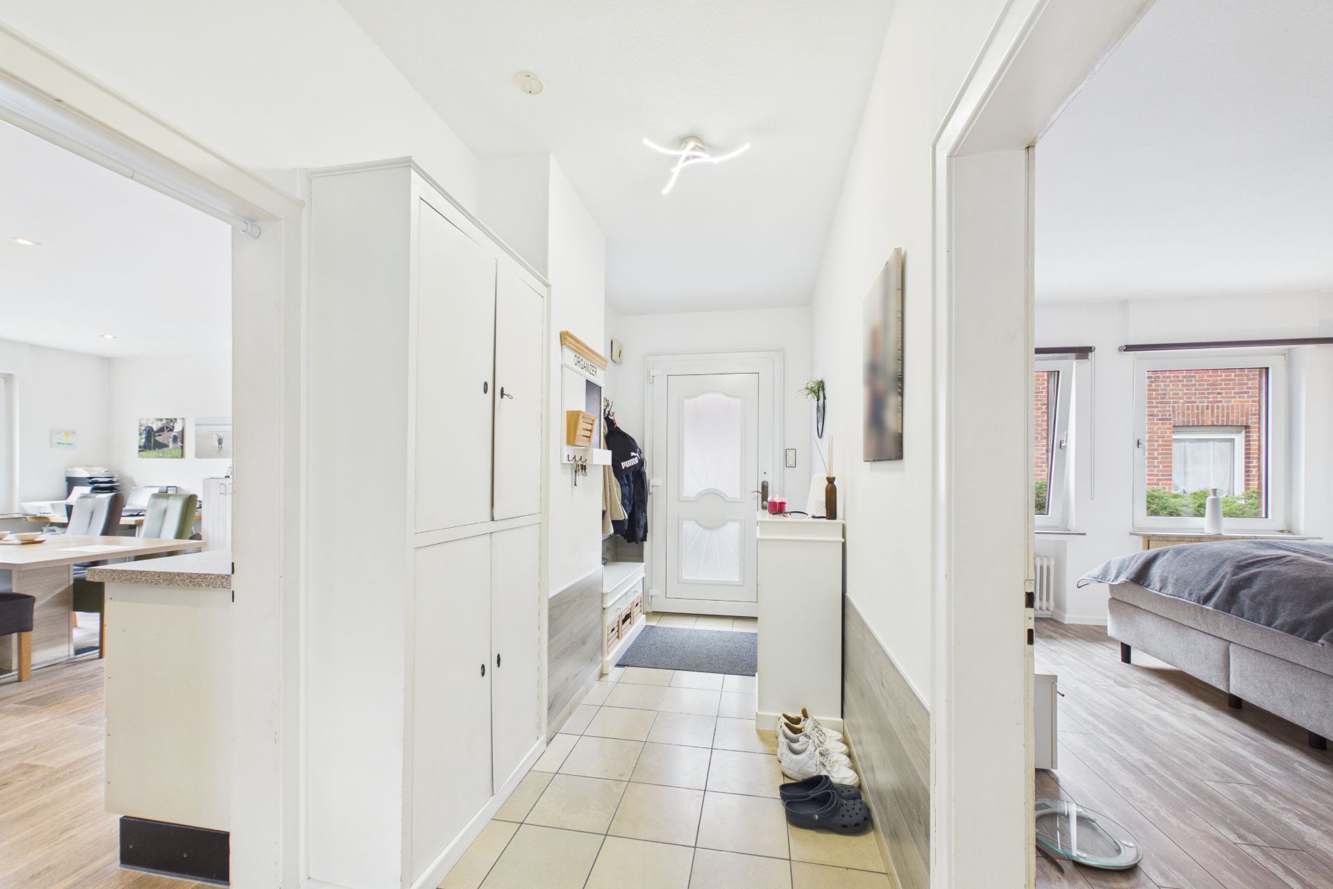 Heller Flur mit Garderobe, Schuhen und Blick in ein Schlafzimmer und Esszimmer.
