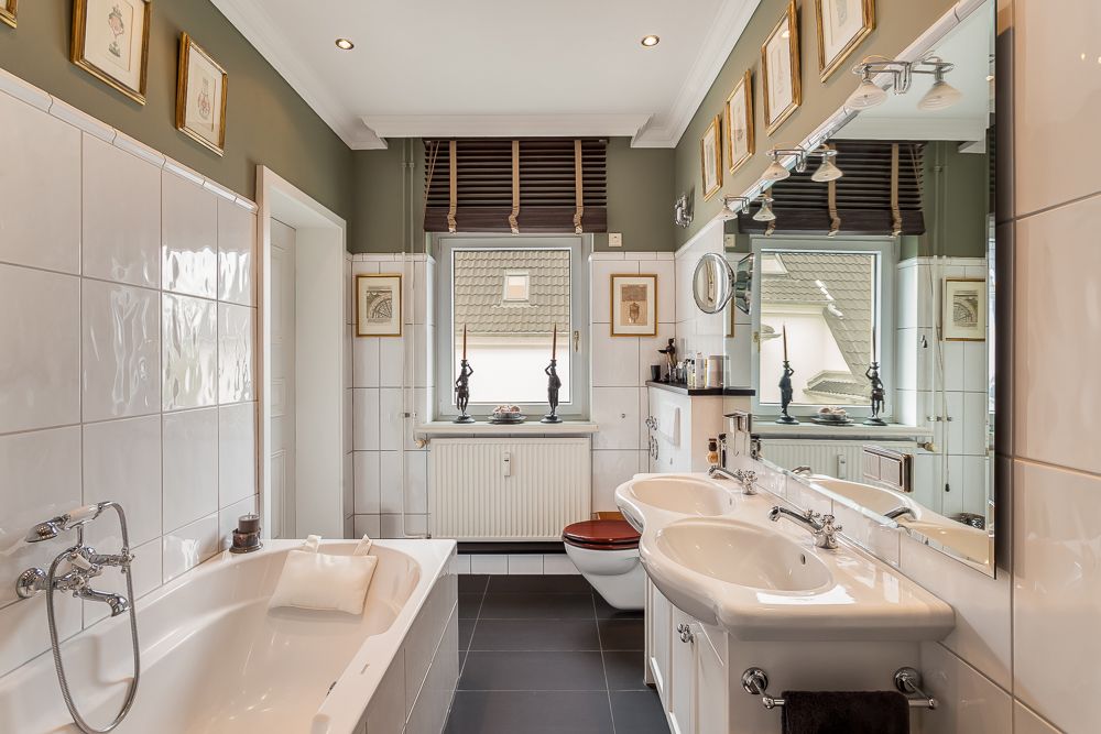 Modernes Badezimmer mit Badewanne, Doppelwaschbecken, Toilette und großem Spiegel.