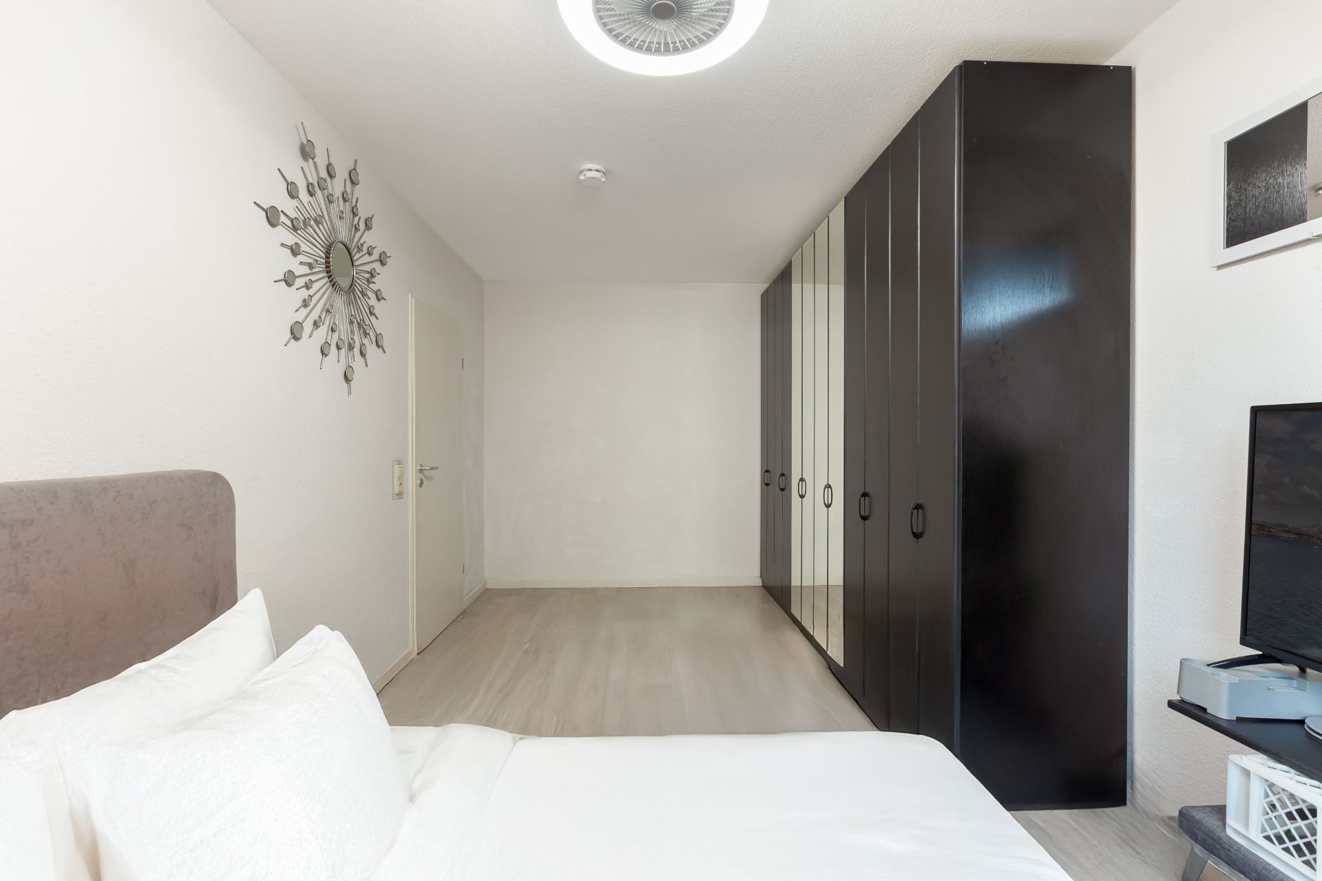 Modernes Schlafzimmer mit großem schwarzen Kleiderschrank und Bett mit weißer Bettwäsche.
