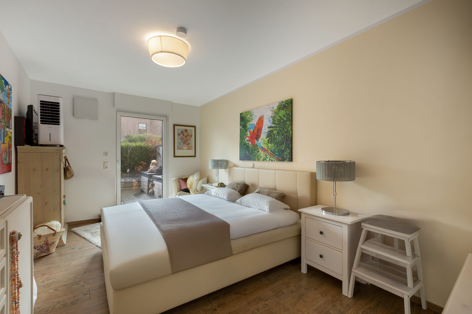 Helles Schlafzimmer mit Doppelbett, Nachttischen, Lampen und Zugang zur Terrasse.