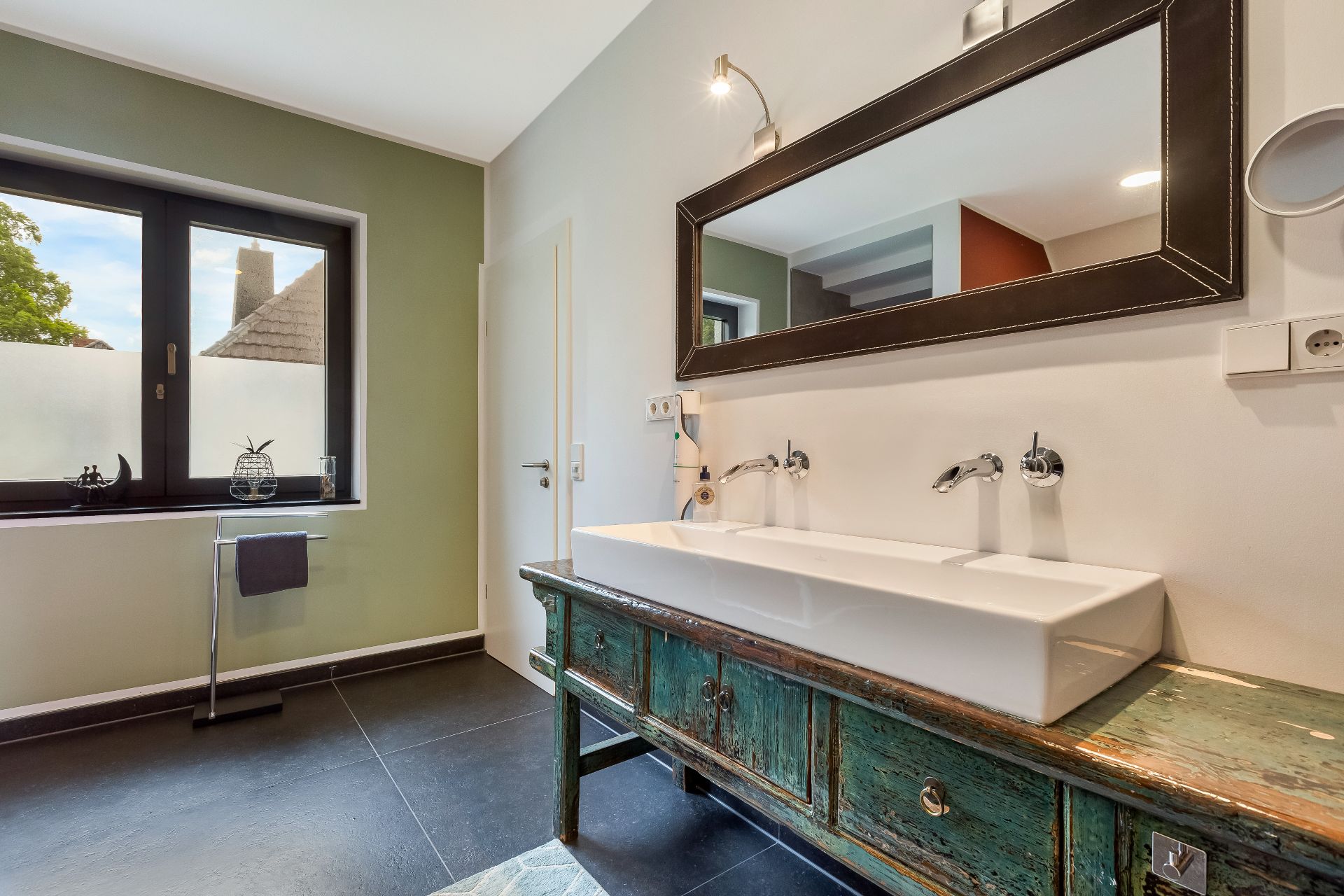 Modernes Badezimmer mit großem Spiegel, Doppelwaschbecken und einem Fenster.
