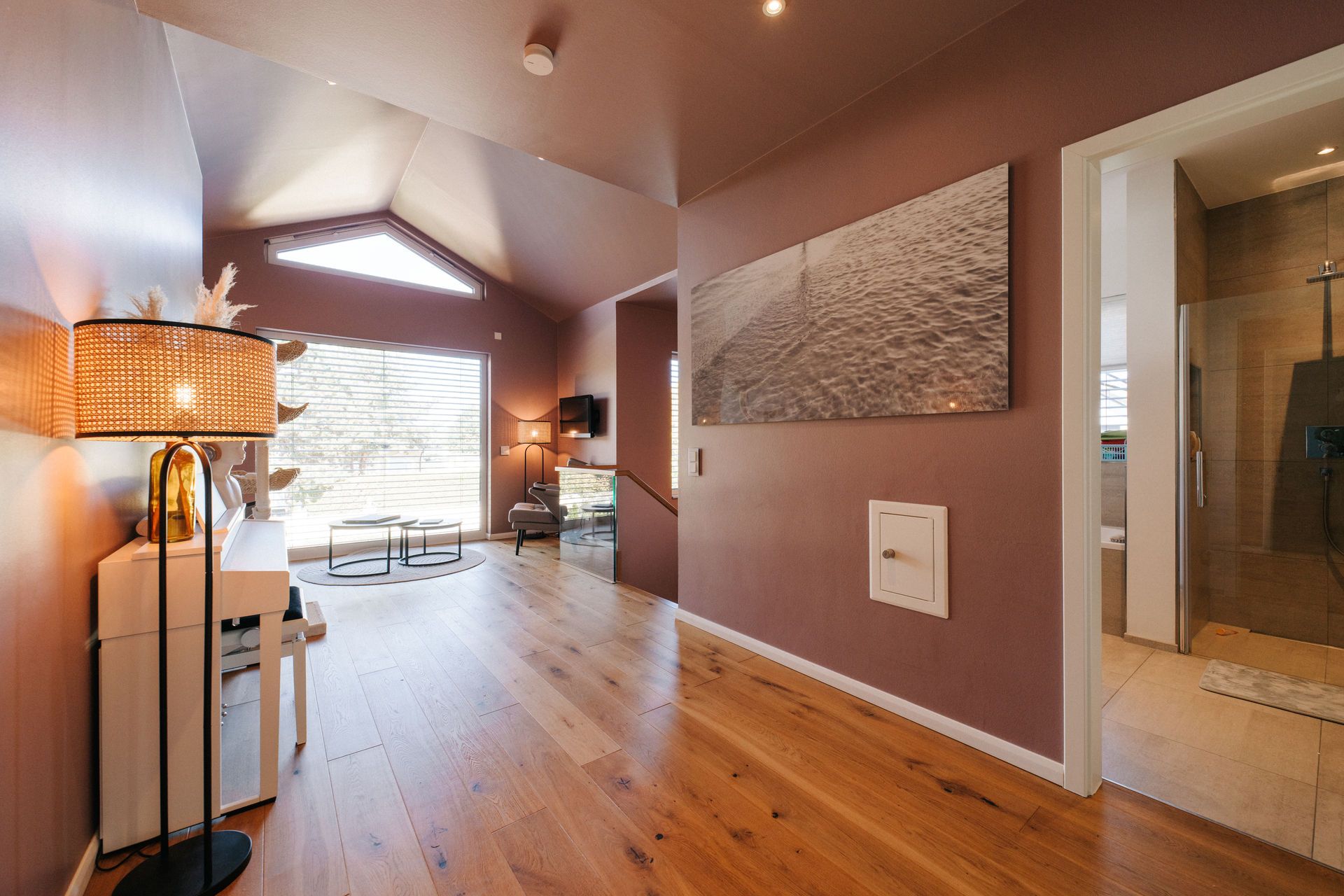 Heller Flur mit Holzboden, Sitzbereich und Blick ins moderne Badezimmer.