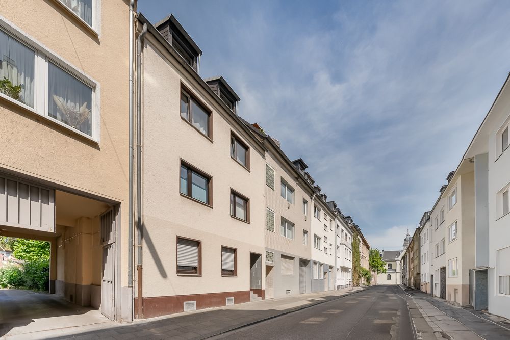 Wohnstraße mit mehrstöckigen Wohnhäusern und Gehweg bei Tageslicht.