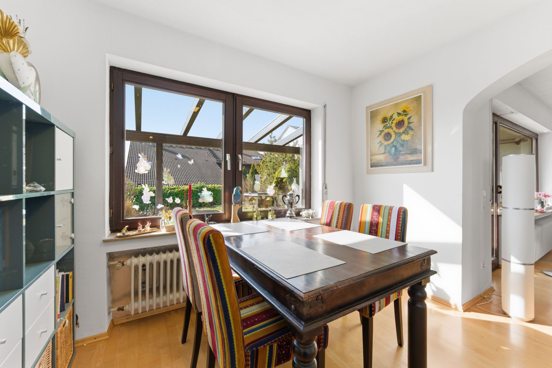 Esszimmer mit bunten Stühlen, großem Fenster und Blick auf den Garten.