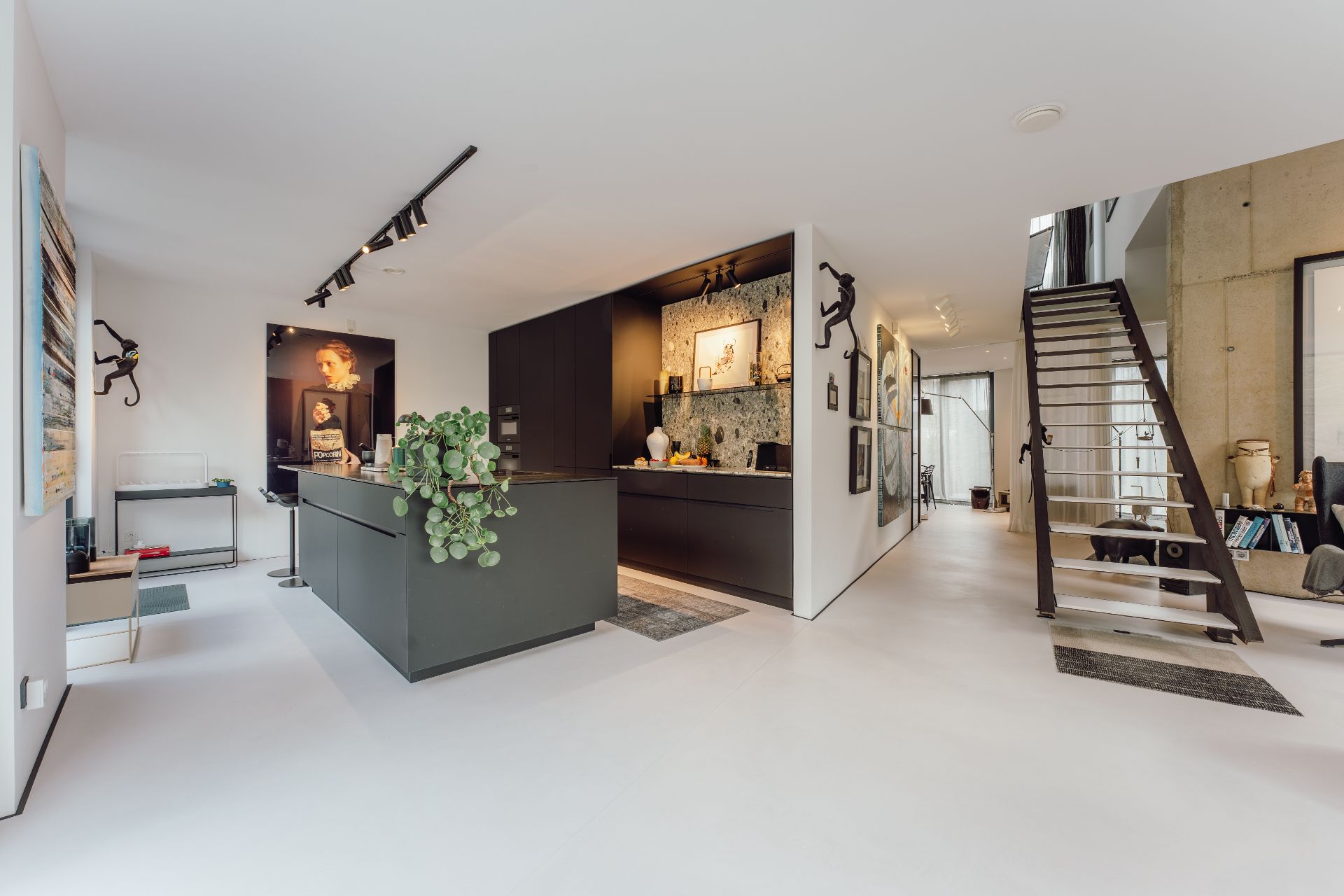 Moderne offene Küche mit schwarzem Schrank, Treppe und dekorativer Kunst an den Wänden.