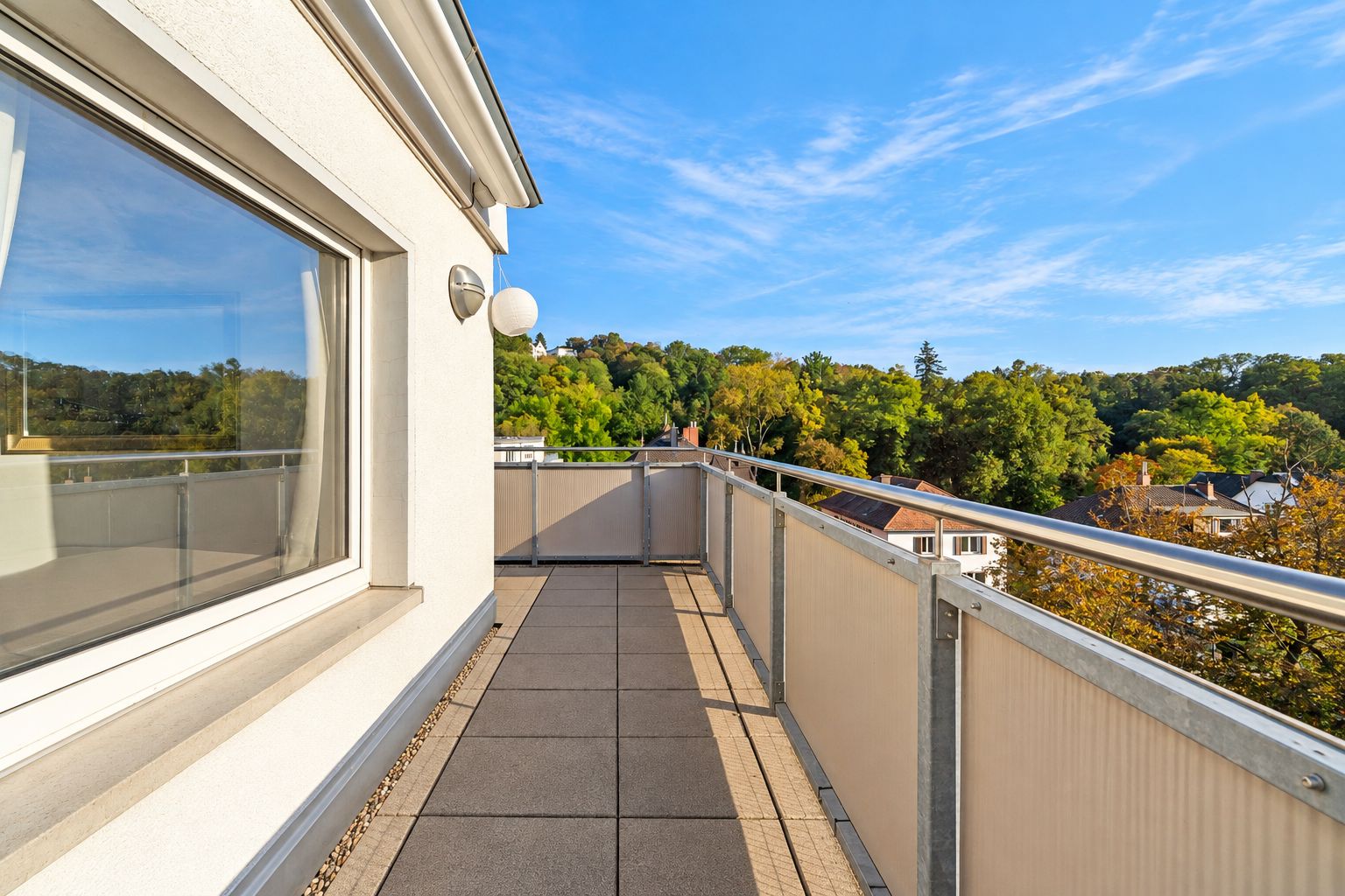 Heller Balkon mit Blick ins Grüne und Metallgeländer an einem Wohnhaus.