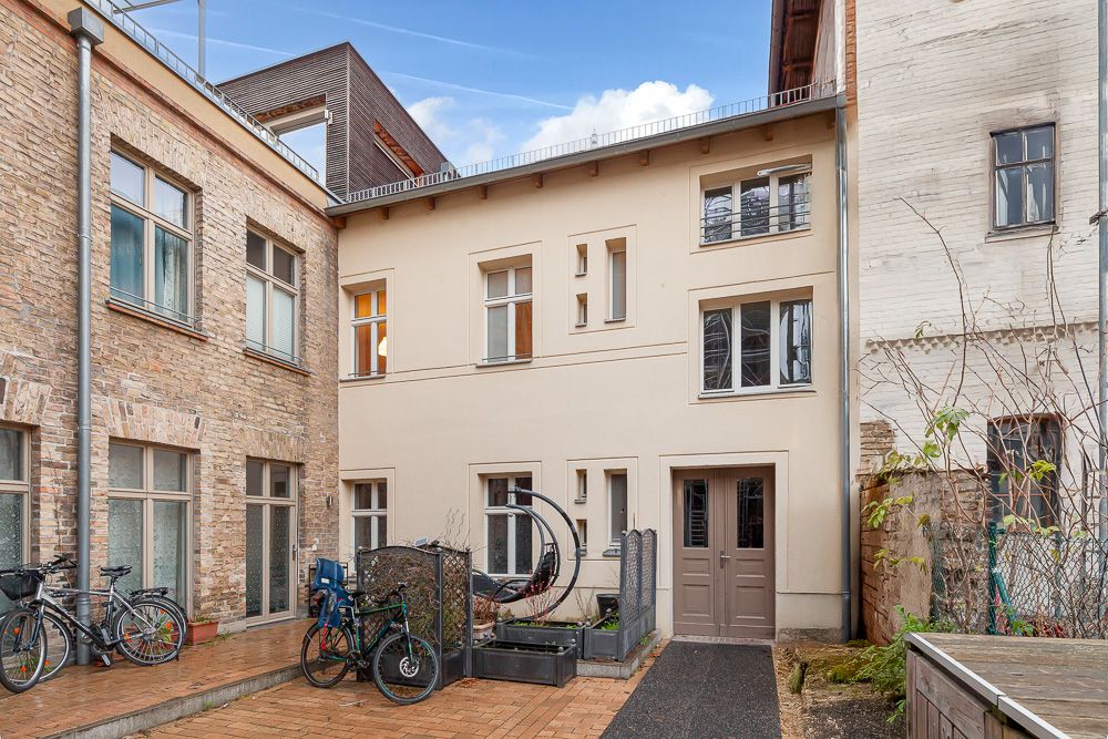Innenhof mit Fahrrädern, Pflanzbeeten und Eingangstür eines Wohnhauses.
