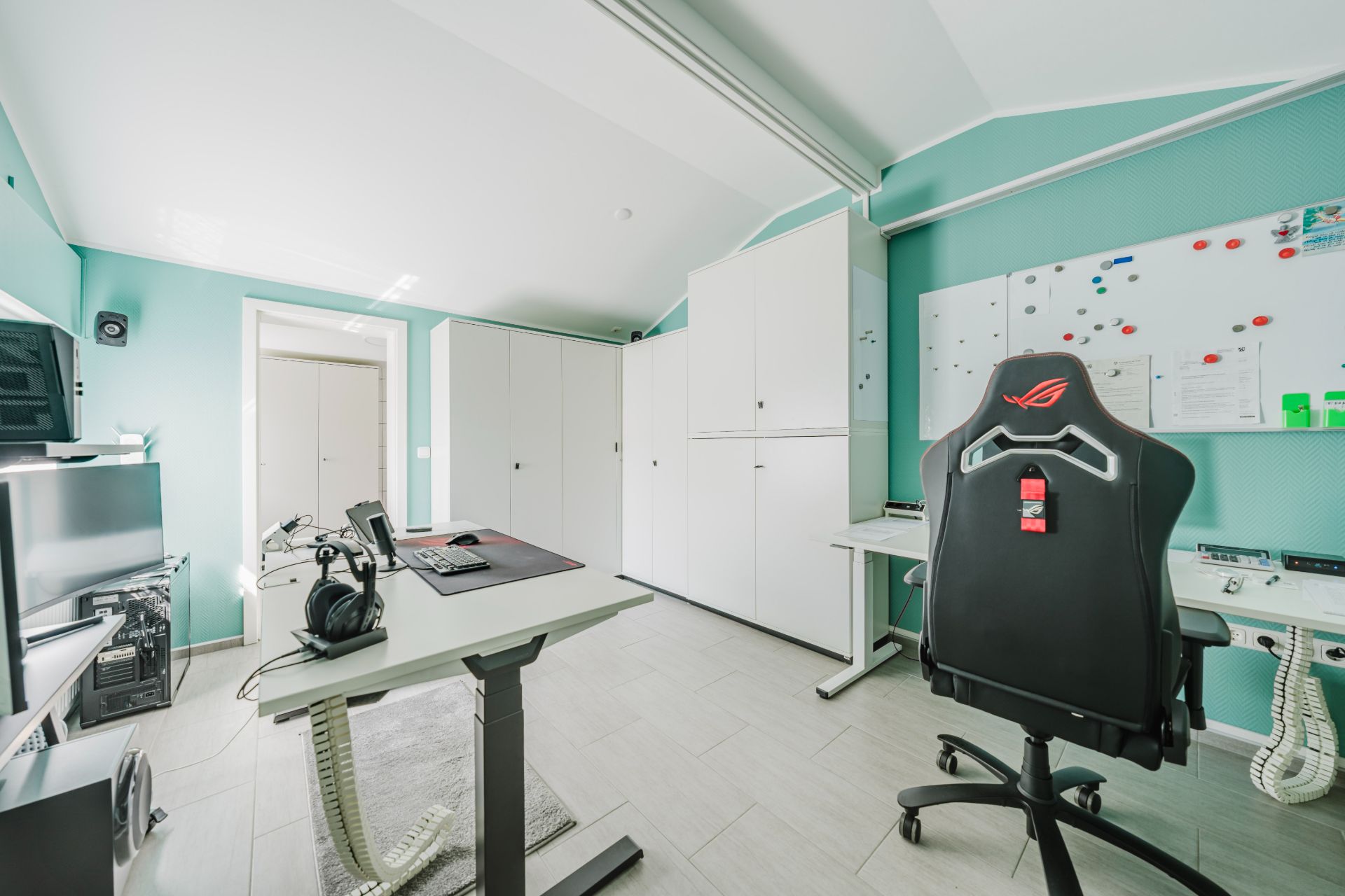 Modernes Arbeitszimmer mit Schreibtisch, Computer, Bürostuhl und weißen Schränken.