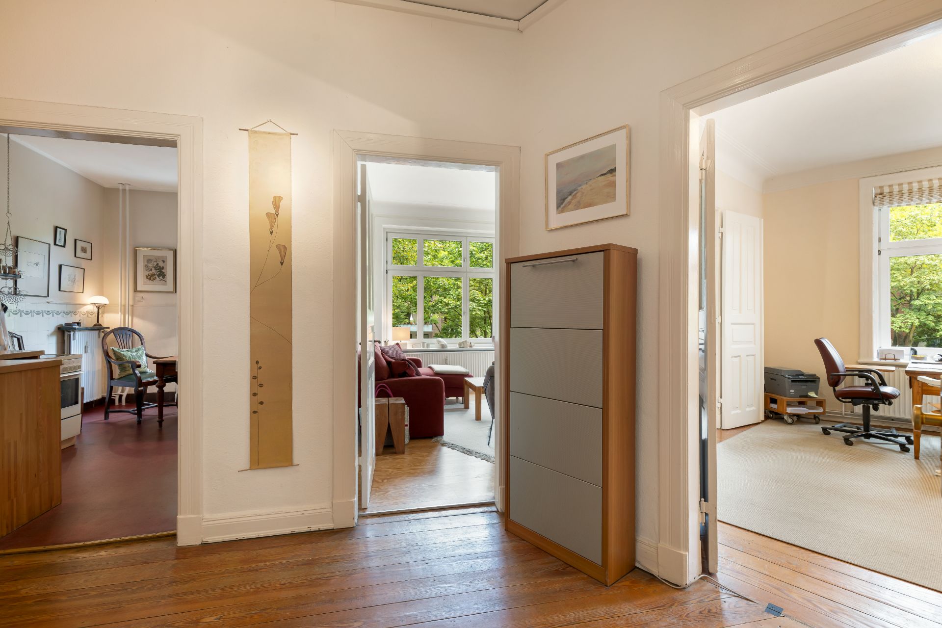 Flur mit Holzboden, Blick in Wohnzimmer, Büro und Küche, viel Tageslicht, moderne Einrichtung.