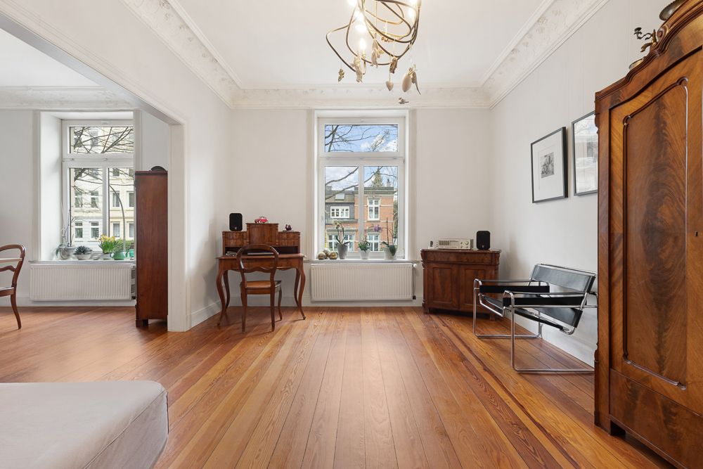 Helles Wohnzimmer mit Holzboden, großen Fenstern und klassischen Holzmöbeln.