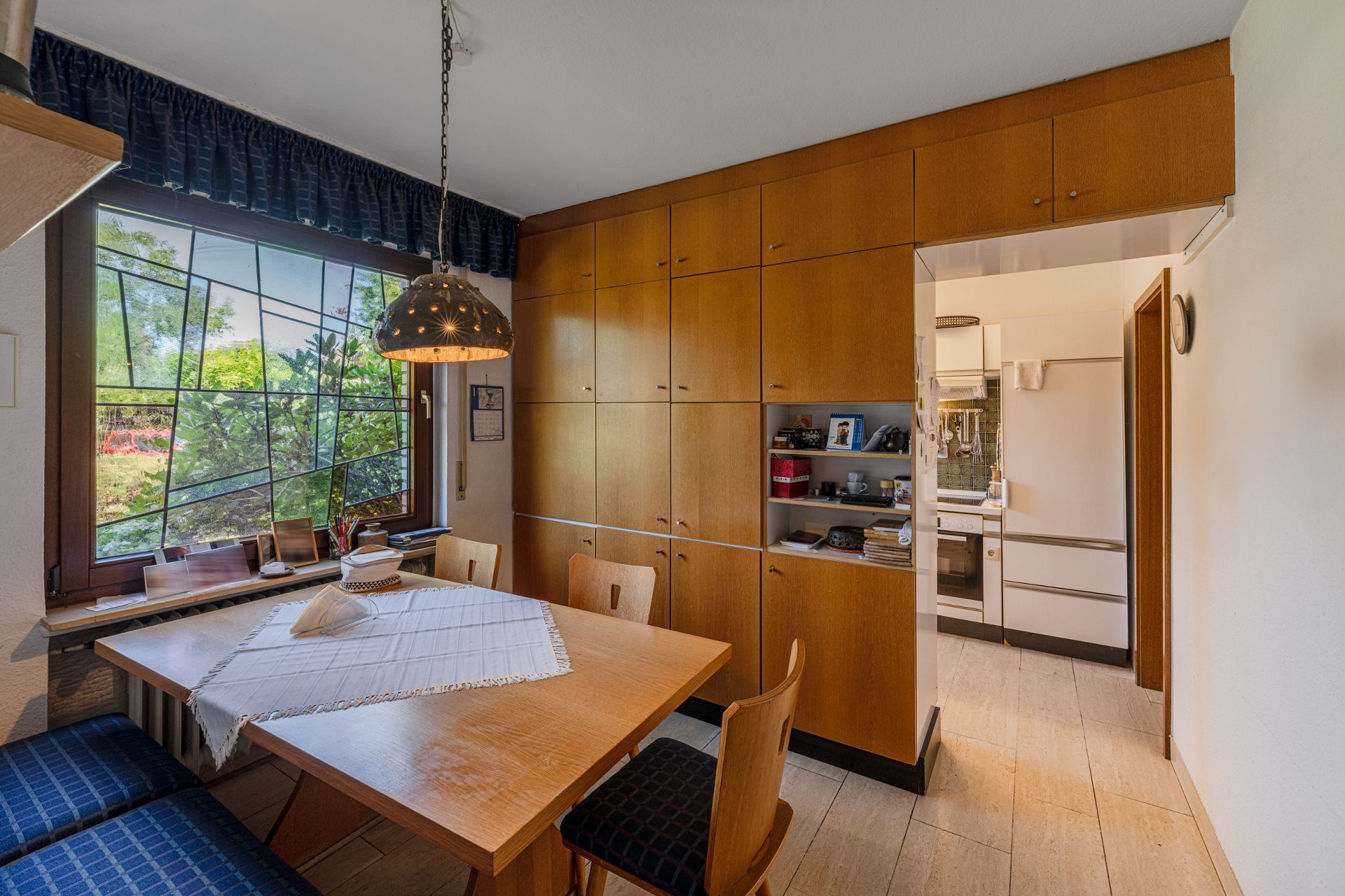 Essbereich mit Holztisch, Stühlen und Einbauschrank, daneben Zugang zur Küche.