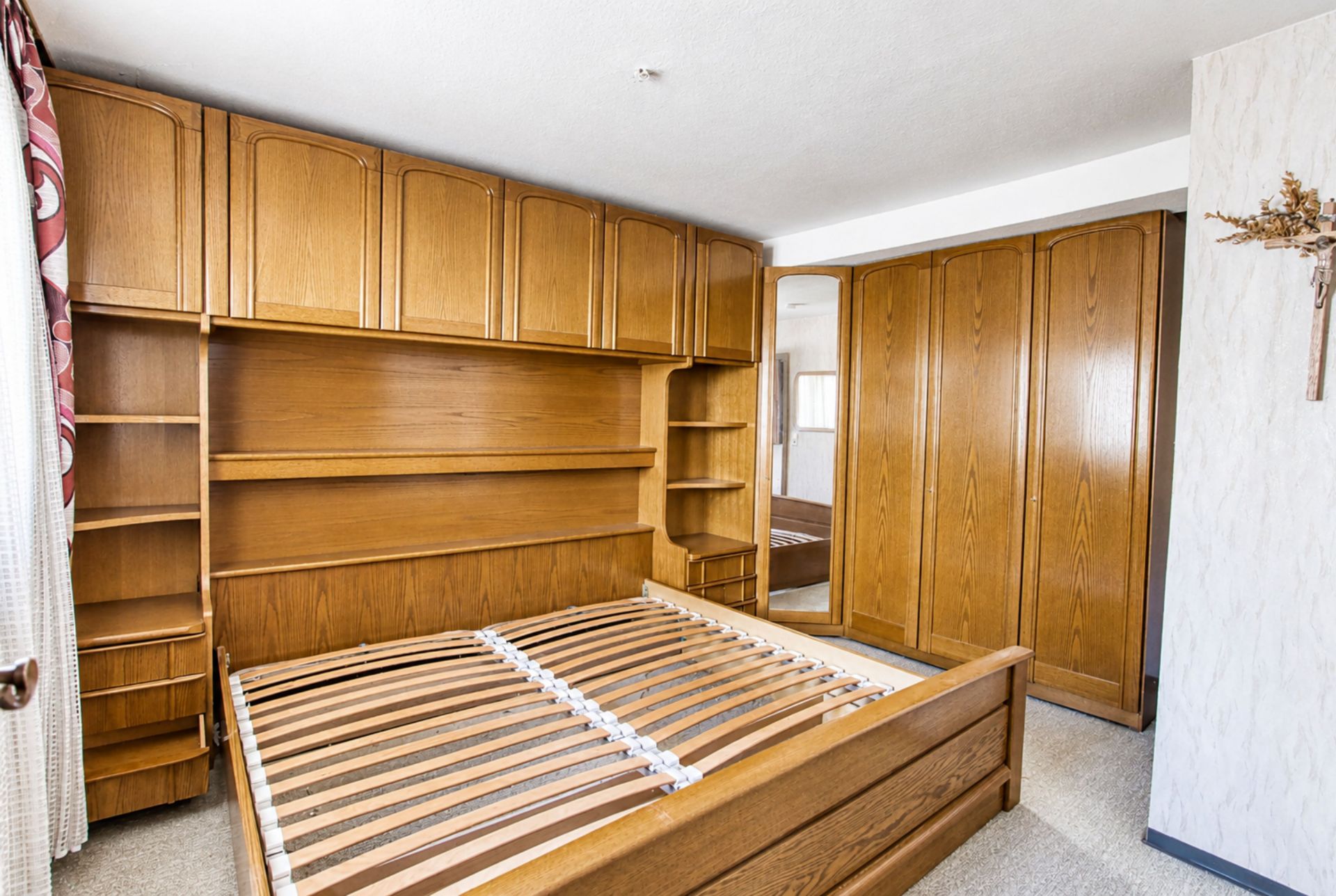 Schlafzimmer mit Holzmöbeln, leerem Bettrahmen und Einbauschränken.
