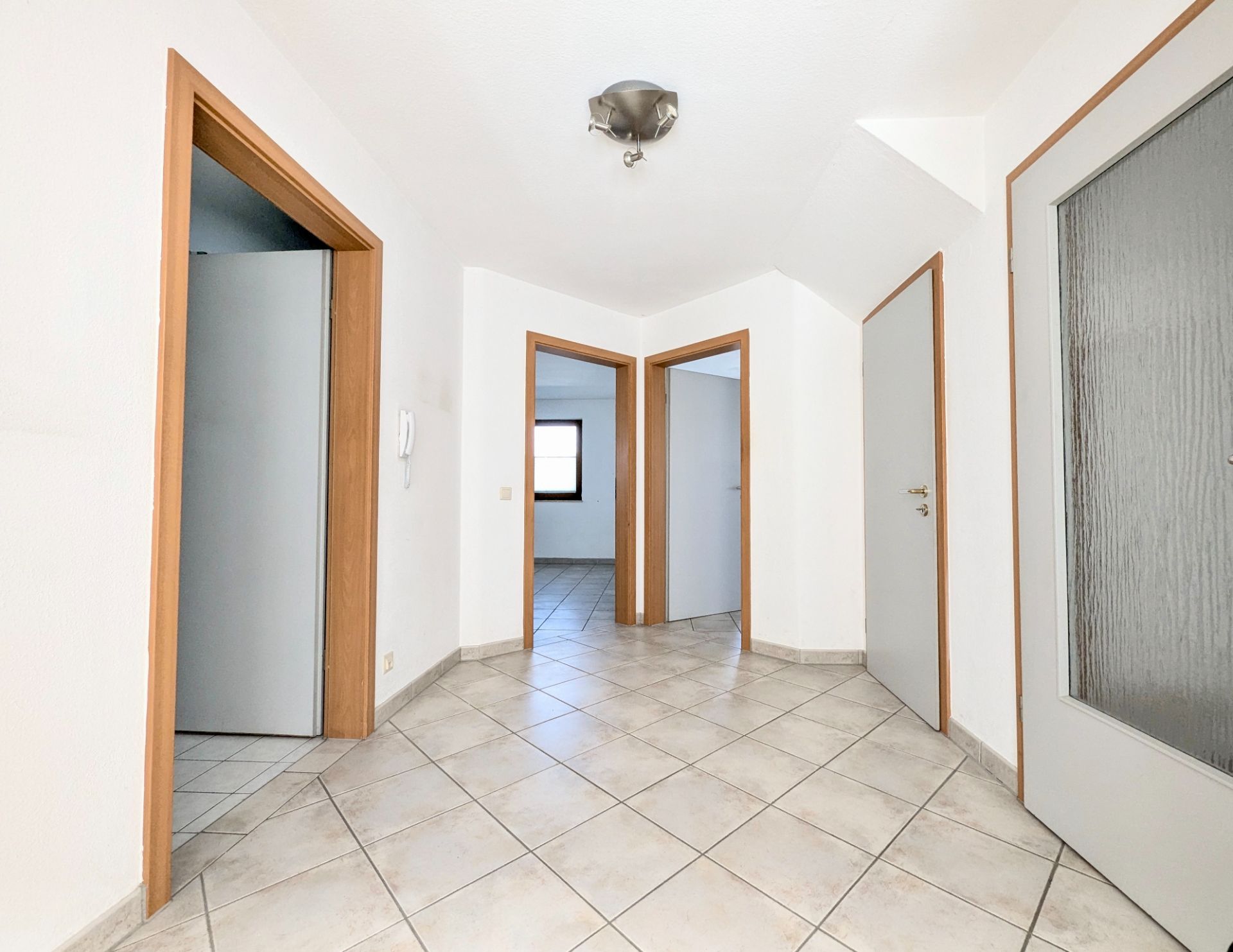 Heller Flur mit Fliesenboden und mehreren Türen in einer Wohnung.