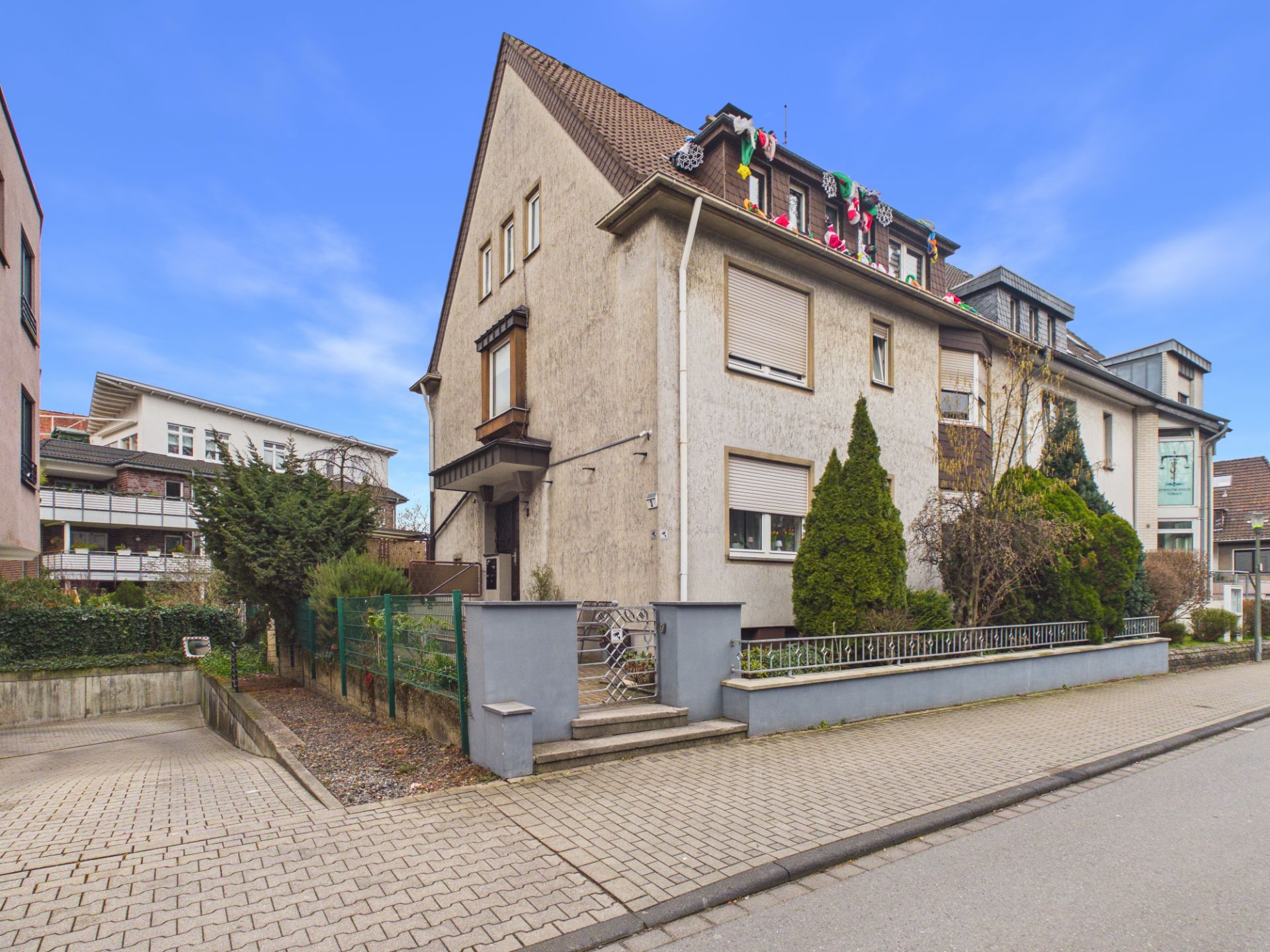 Eckhaus mit Vorgarten, Wintergarten und mehreren Fenstern an einer ruhigen Wohnstraße.