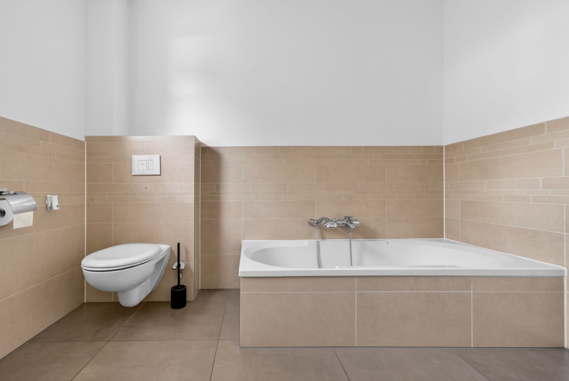 Modernes Badezimmer mit Wandtoilette und rechteckiger Badewanne, beige Fliesen an Wand und Boden.