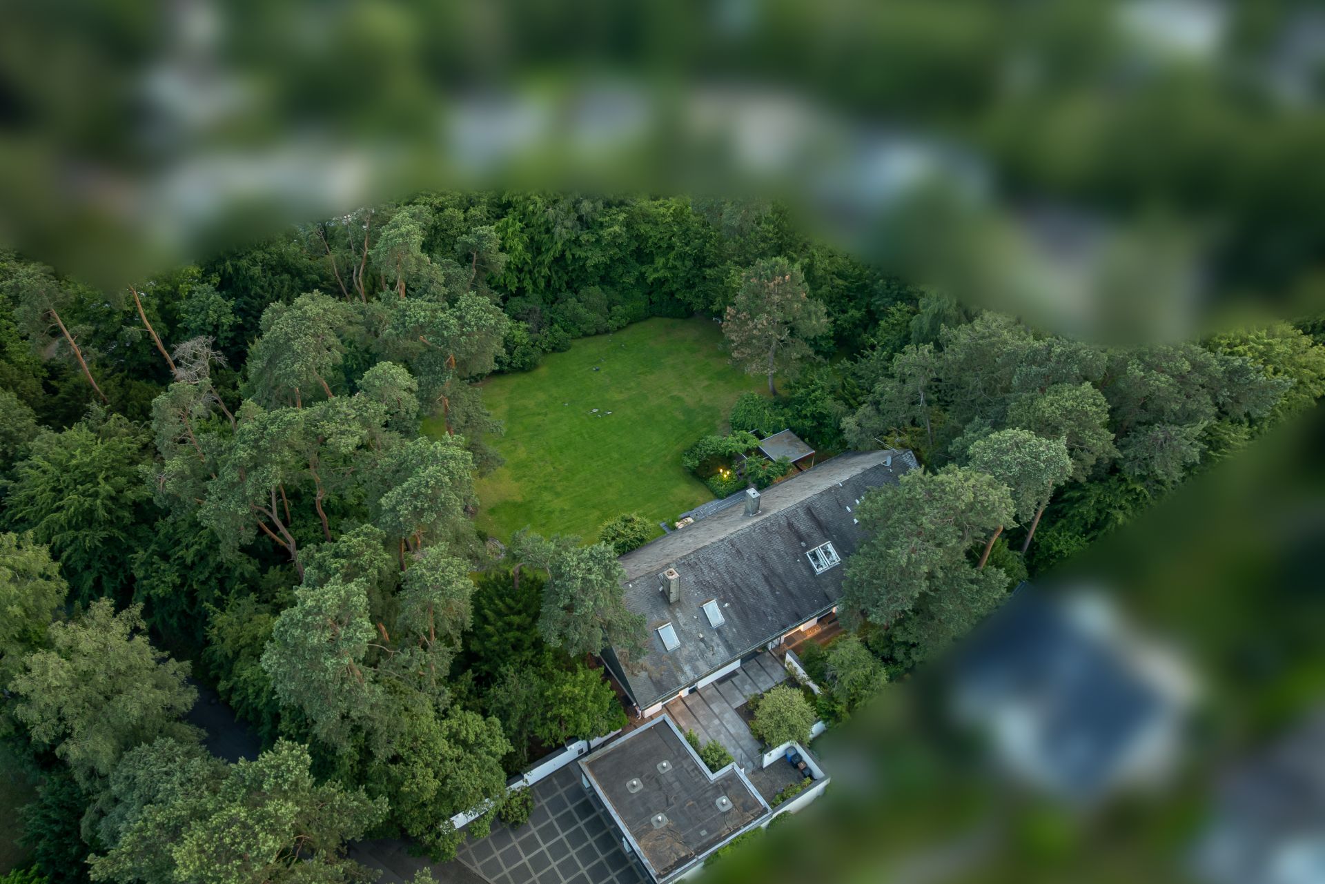 Luftaufnahme eines Hauses mit großem Garten und umgebenden Bäumen.