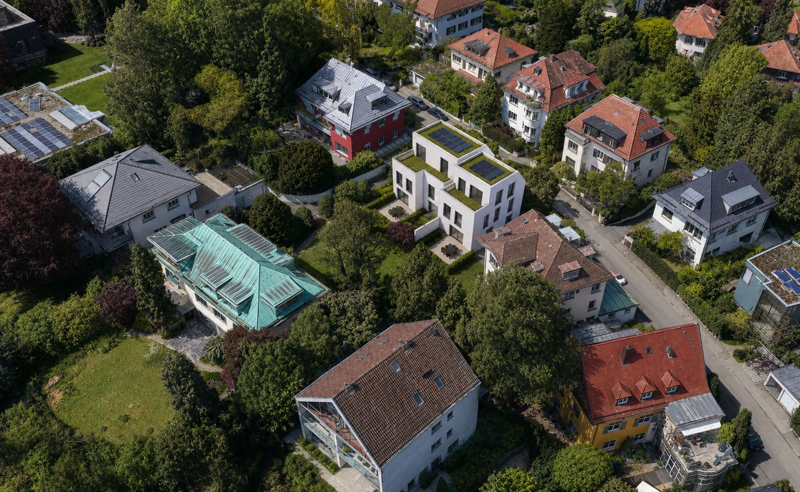 Luftaufnahme von Wohnhäusern und grünen Gärten in einem ruhigen Wohnviertel.
