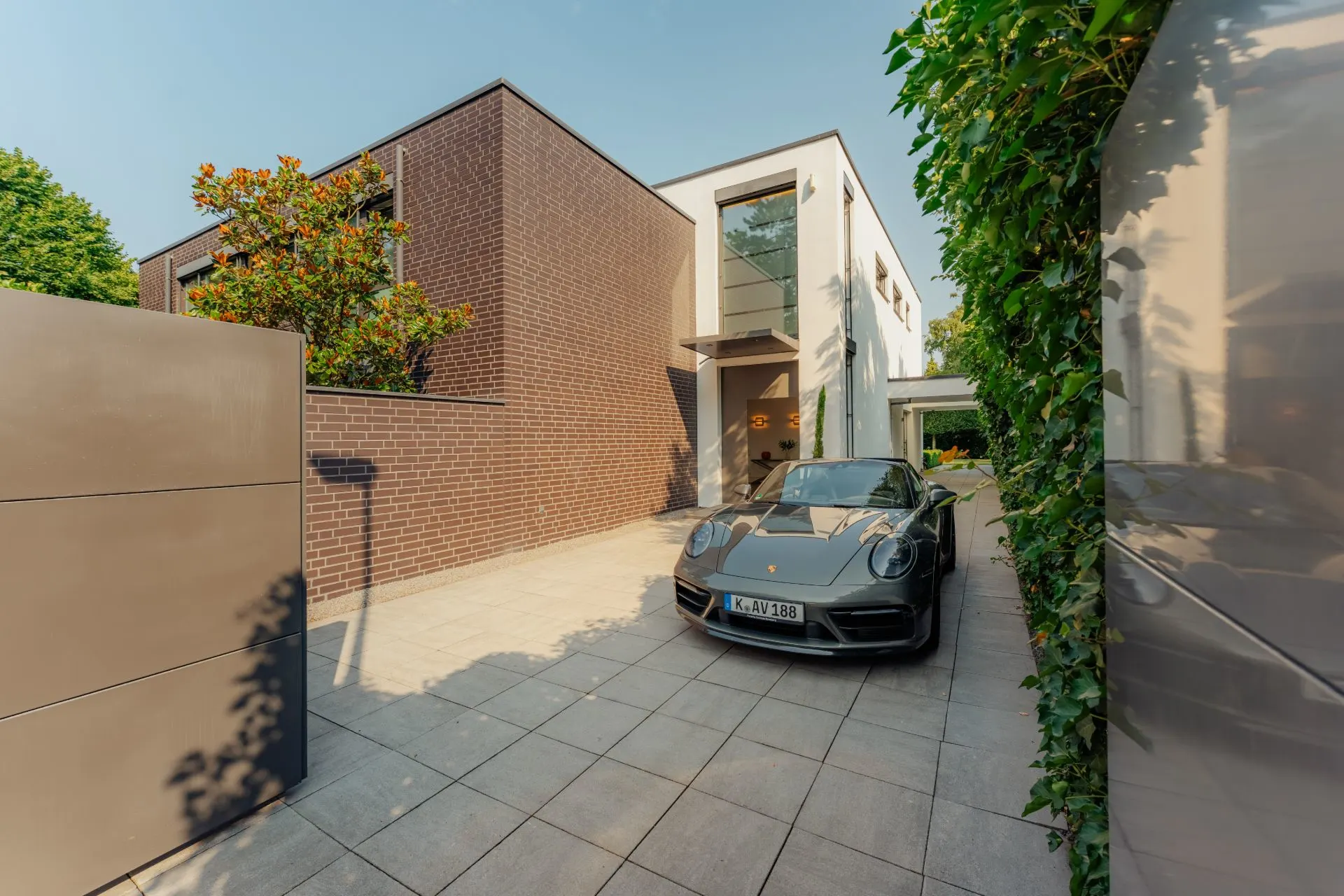 Moderne Wohnhausfassade mit einem schwarzen Auto in der Einfahrt.
